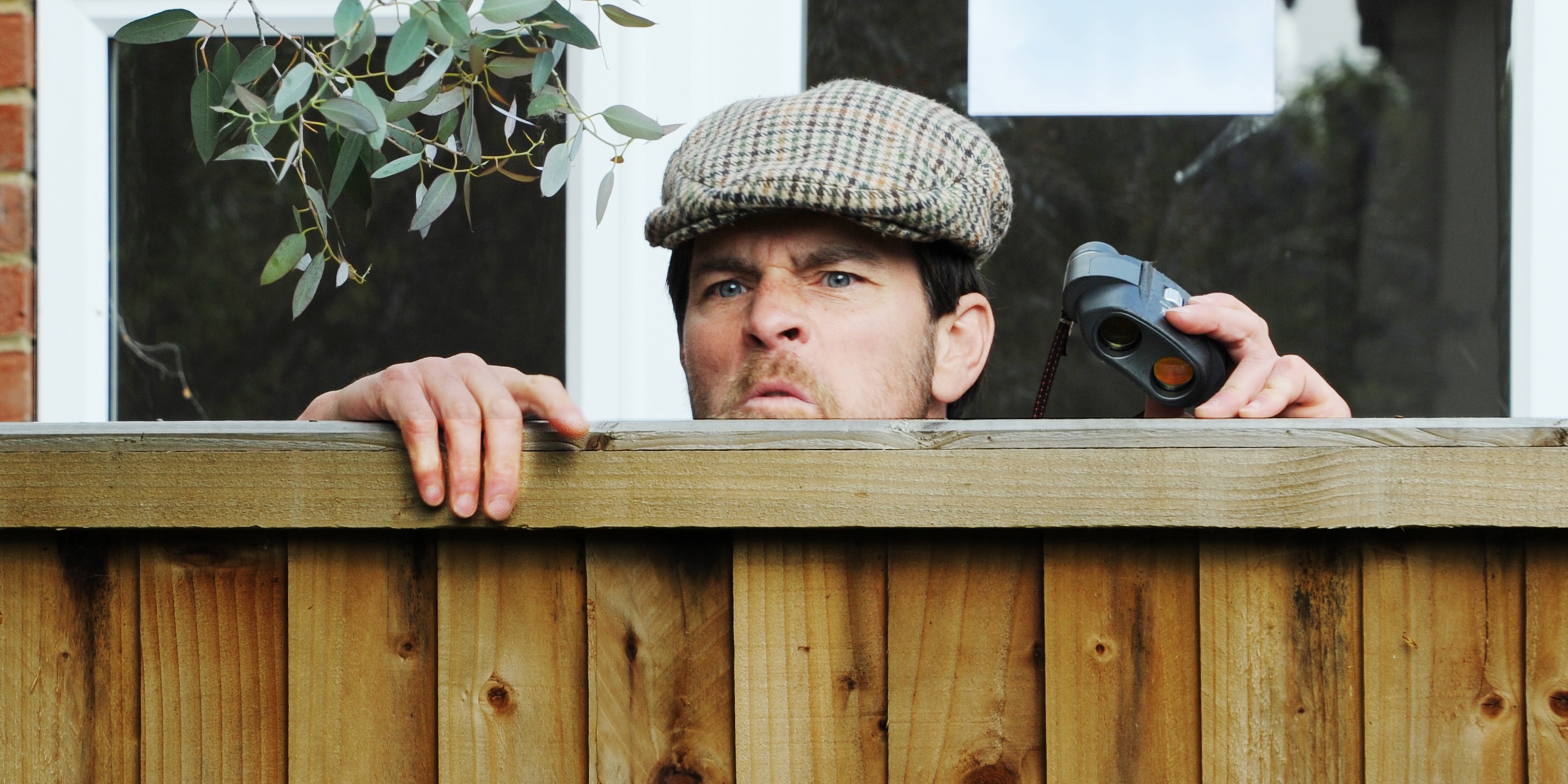 A man peering over a fence | Source: Shutterstock