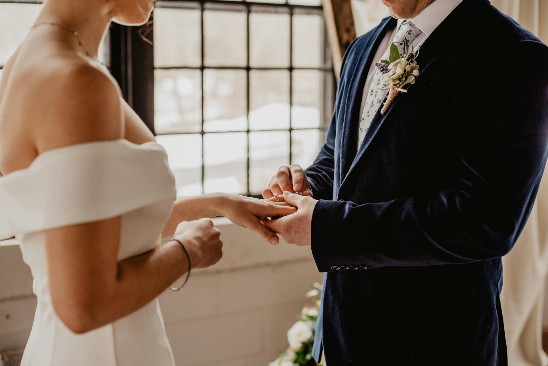 A close-up shot of a groom placing a wedding ring on his bride's finger | Source: Pexels