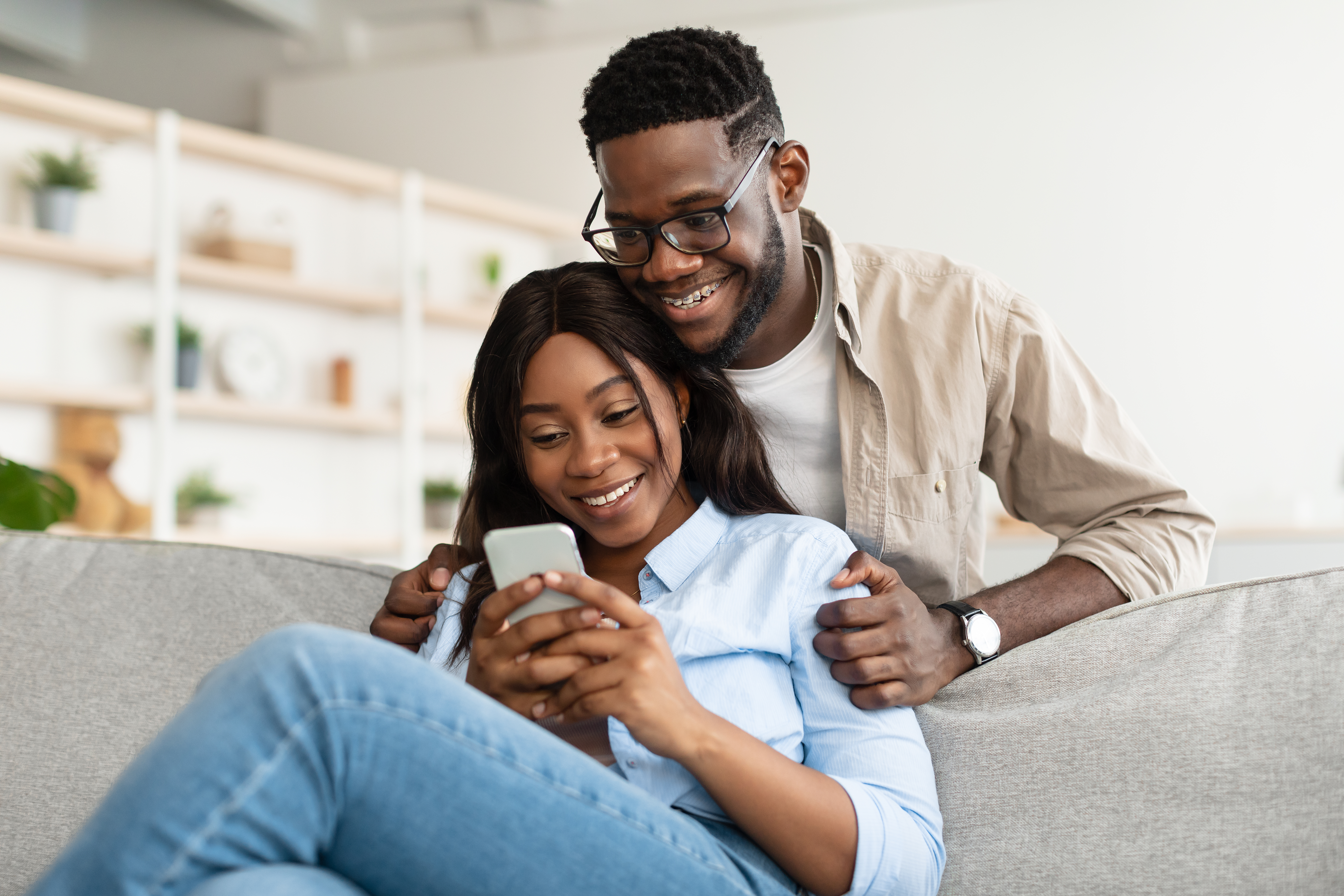 African american couple sitting on couch, using cellphone | Source: Getty Images