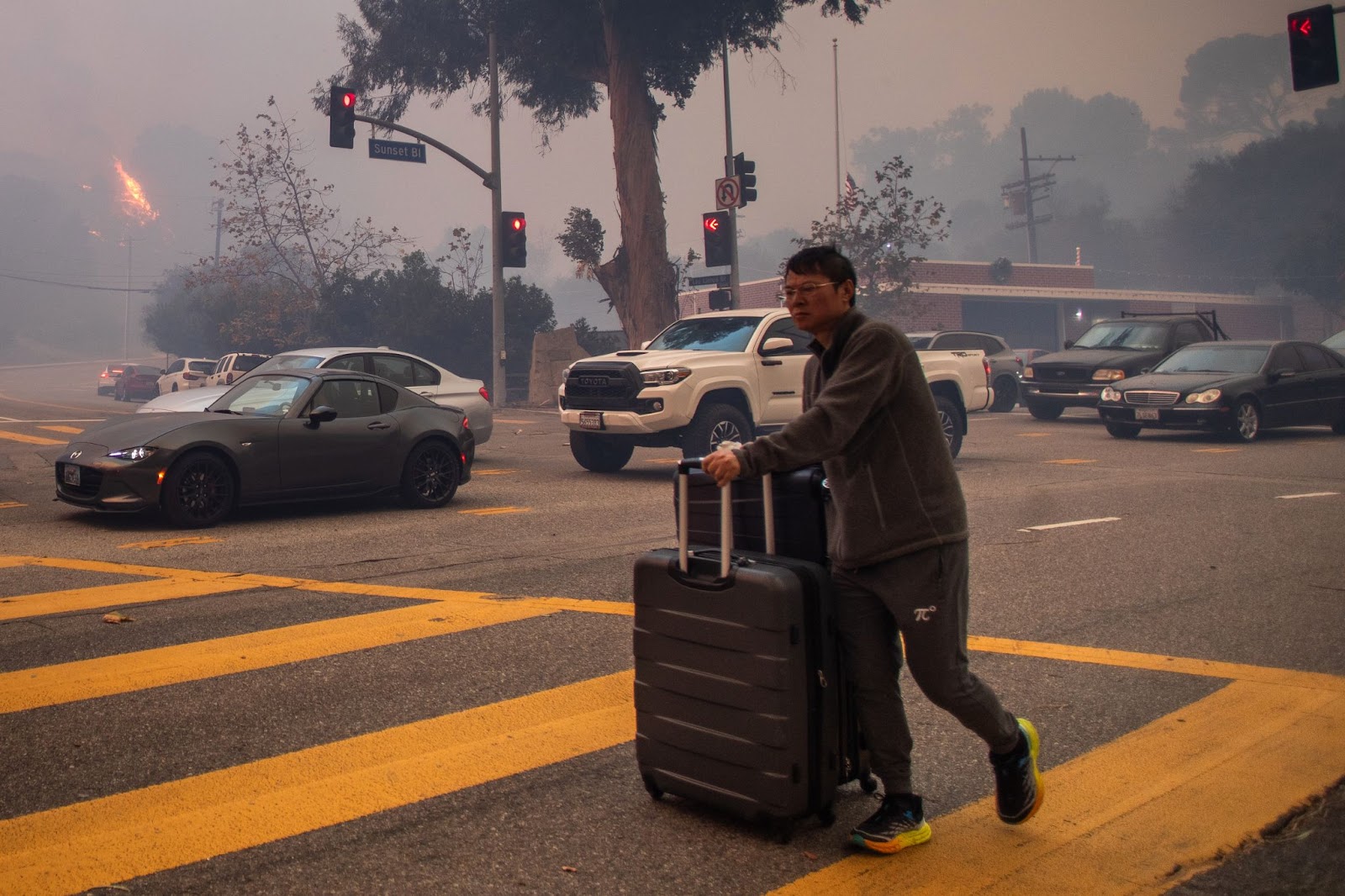 A man evacuating along Sunset Boulevard as the fire burns amid a powerful windstorm on January 7, 2025, in the Pacific Palisades neighborhood of Los Angeles, California. | Source: Getty Images