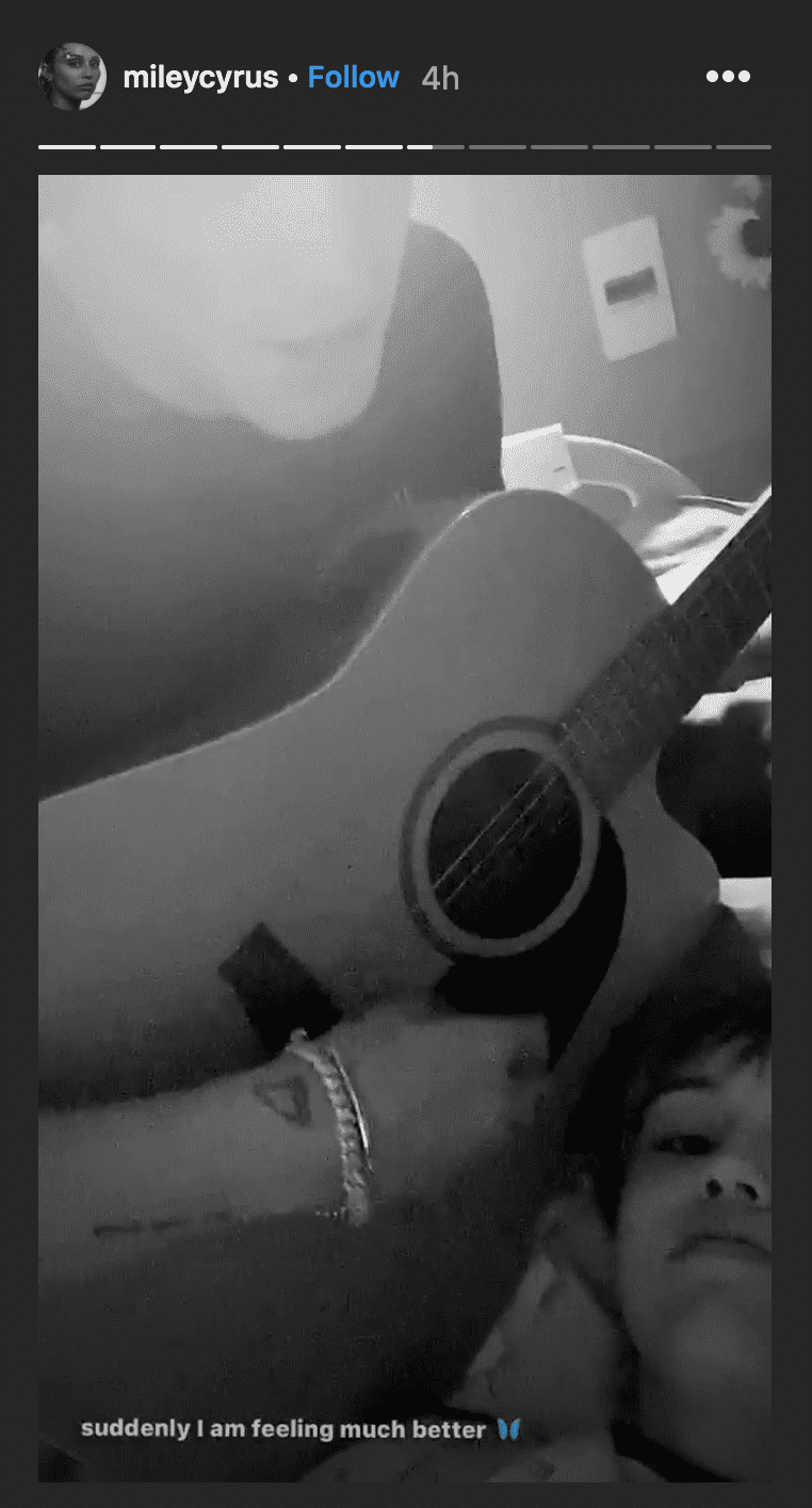 As she's taken in for tonsillitis, Miley Cyrus shares a picture of Cody Simpson playing on his guitar and singing music to her while laying on her hospital bed | Source: instagram.com/mileycyrus