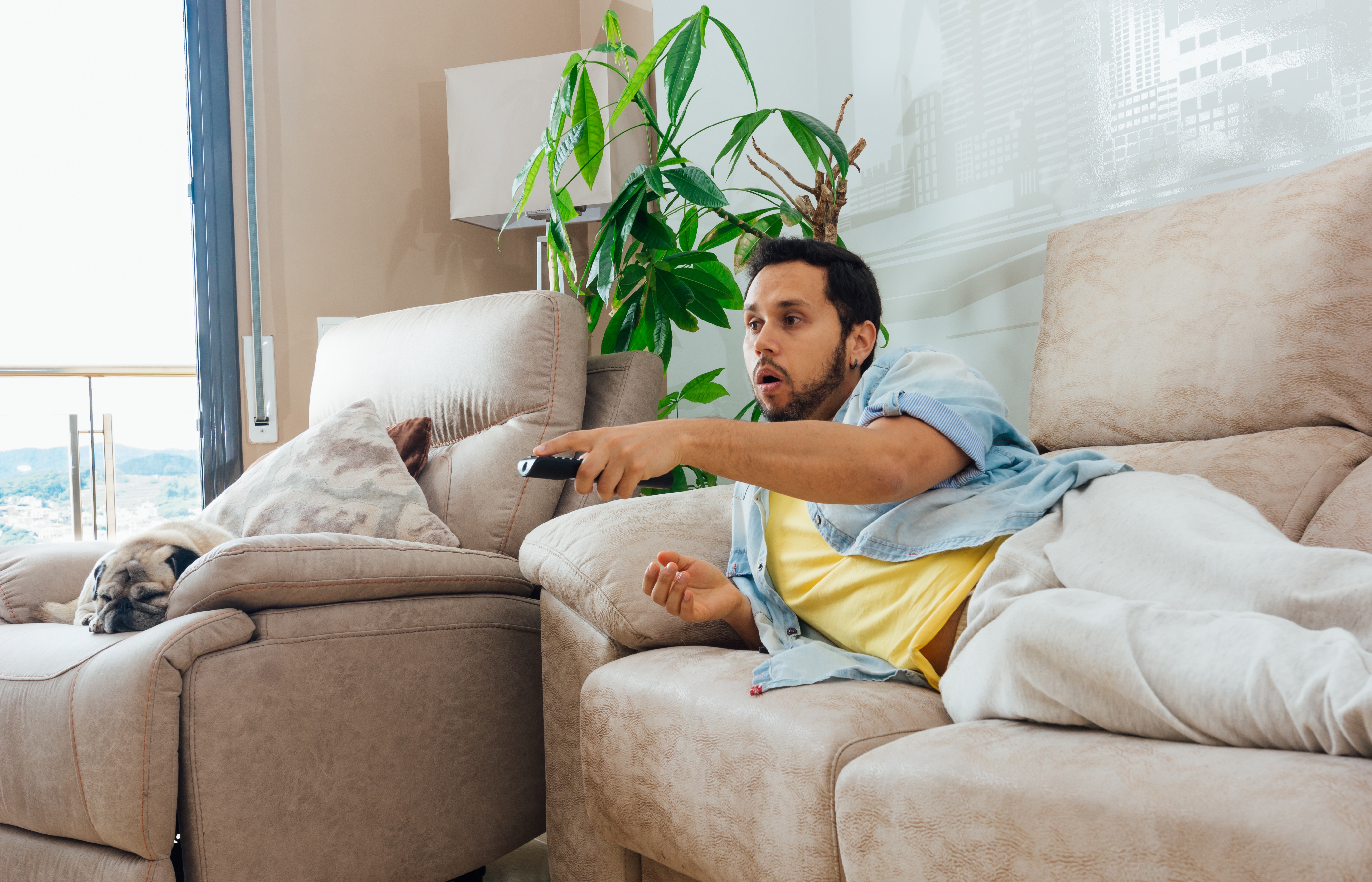 Man lounging on a couch with the TV remote | Source: wirestock on Freepik