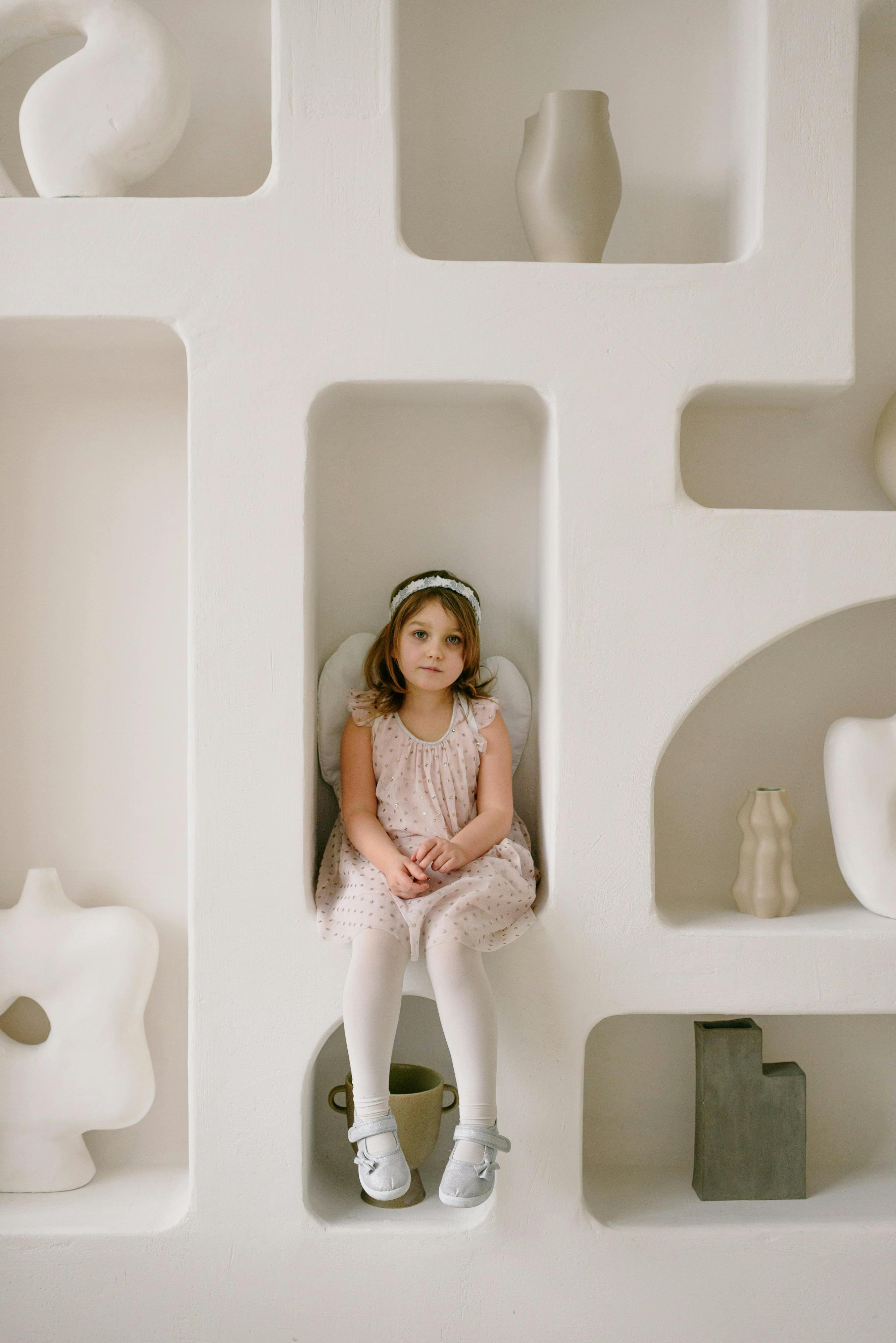 A sad girl sitting on a shelf | Source: Pexels