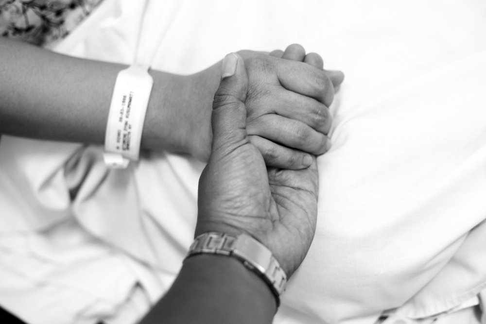 Dos personas tomadas de la mano con brazaletes de hospital. I Foto: Shutterstock