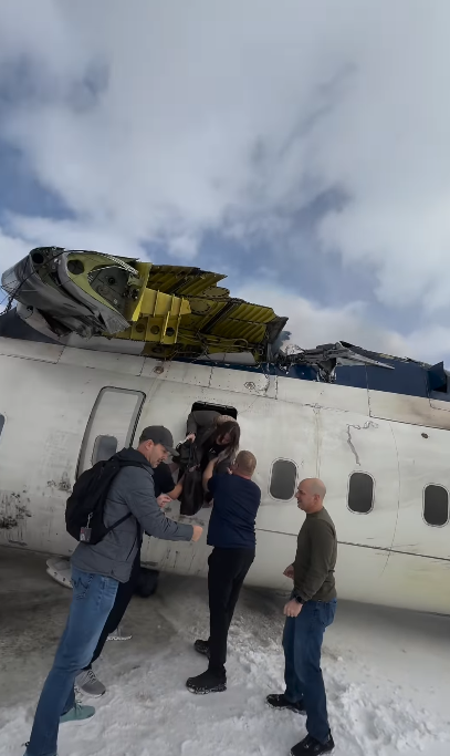 A passenger climbs through an emergency exit while other individuals assist them down from the wrecked fuselage, from a video dated February 18, 2025 | Source: Instagram.com/eggxit