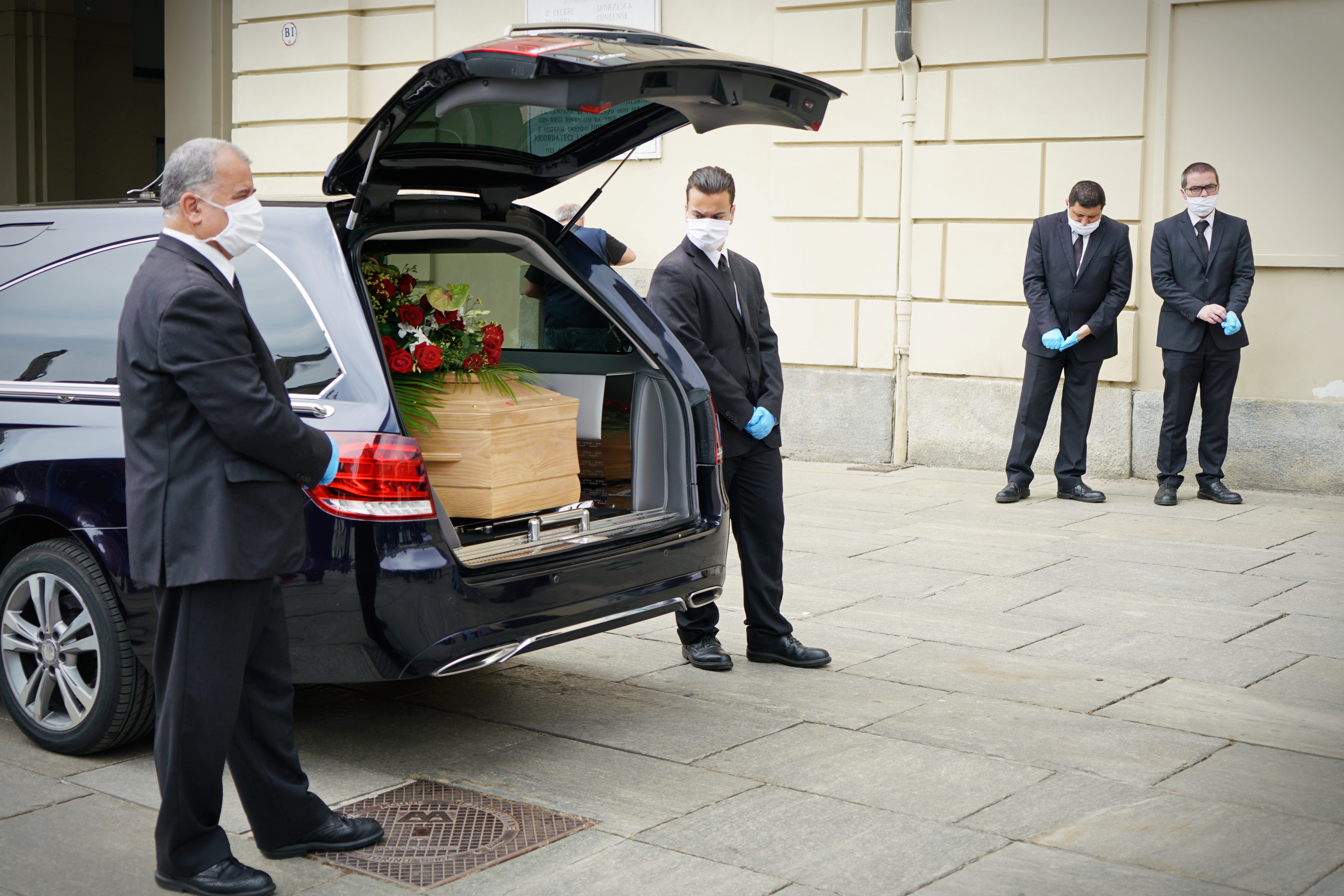 People gathered outside a hearse carrying a coffin | Source: Shutterstock