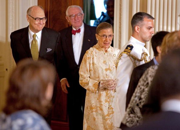 U.S. Supreme Court Associate Justice Ruth Bader Ginsburg (C) with Associate Justice John Paul Stevens (2nd L) during a reception for new Supreme Court Associate Justice Sonia Sotomayor in the East Room of the White House August 12, 2009, in Washington, DC. | Source: Getty Images.
