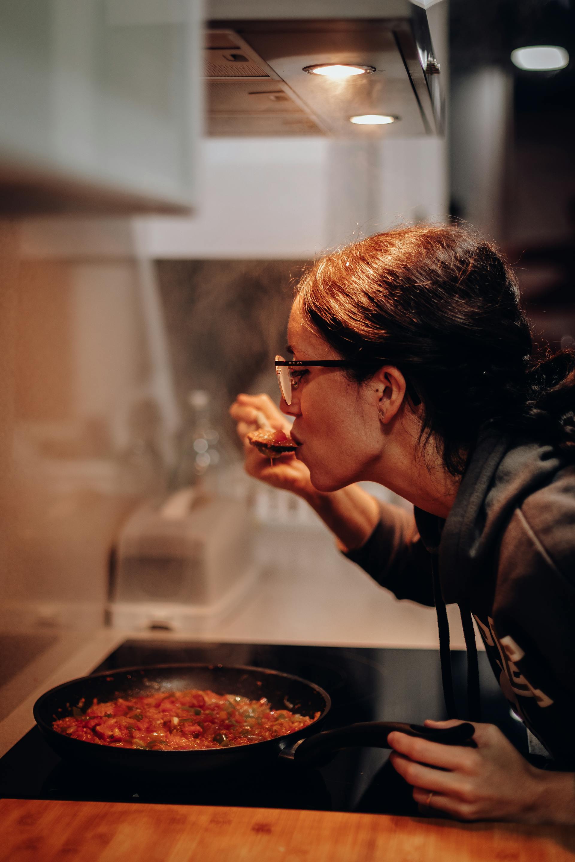 Una mujer degustando de una sartén | Fuente: Pexels