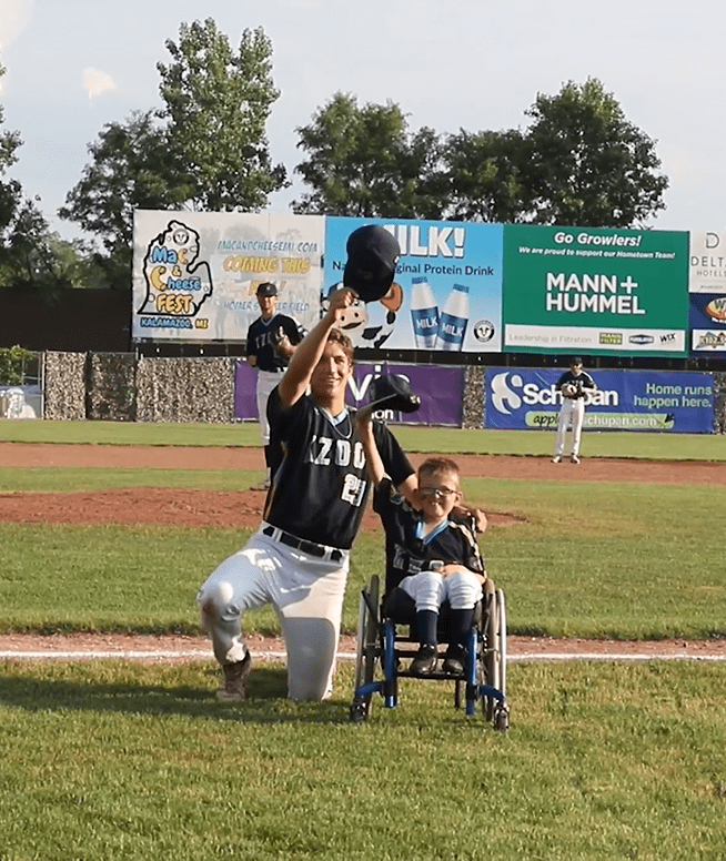 Brenden Lowery and a player for the baseball team Kalamazoo Growlers tip their caps off for the crowd. │Source: Facebook/kzoogrowlers