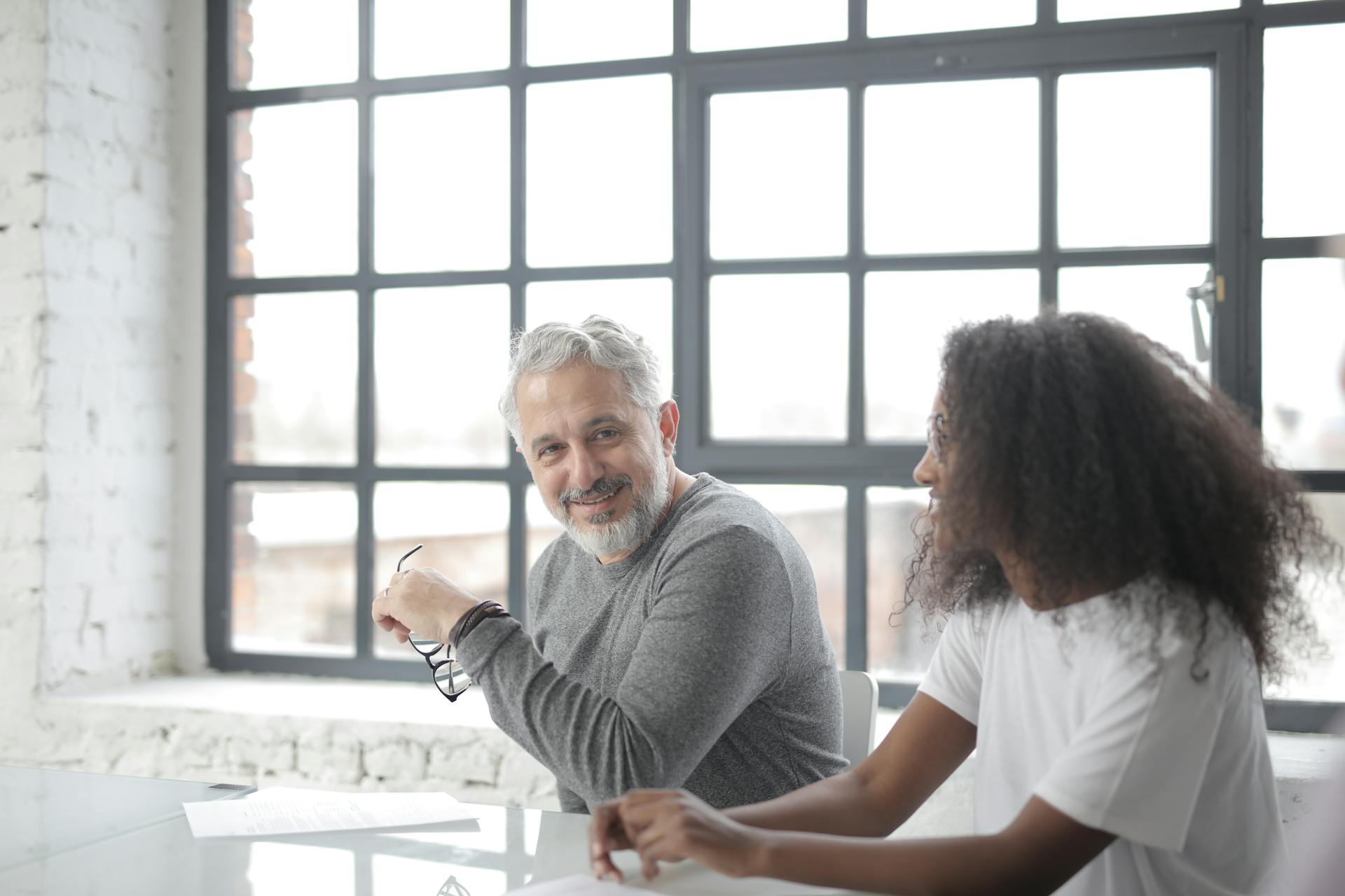 A senior man mentoring a young black female colleague in an office setting | Source: Pexels