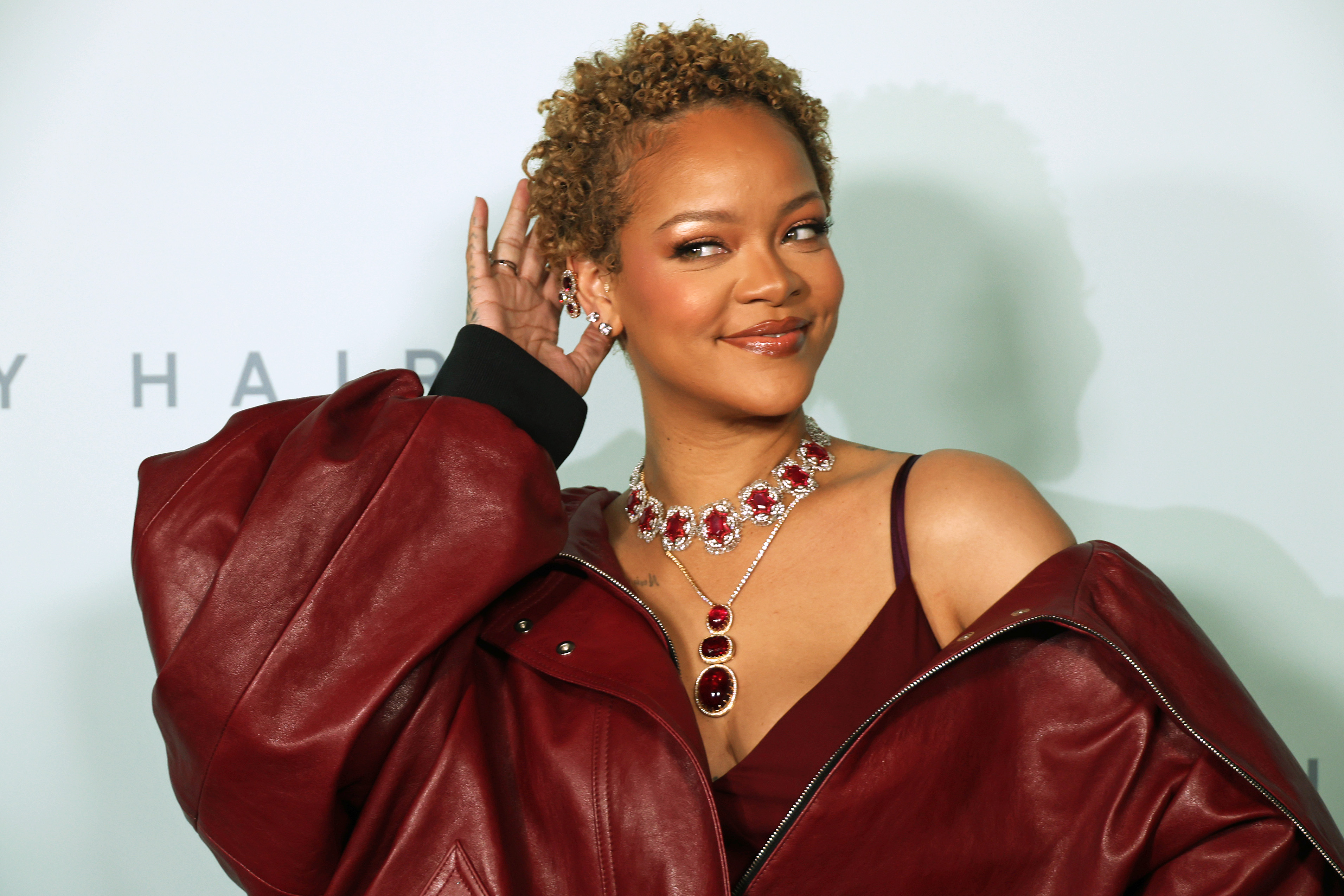 Rihanna arrives at the Fenty Hair launch glowing in rich berry tones that echo her jewel-studded necklace. Her short golden curls add effortless radiance against the bold leather on her shoulders, and with a knowing smile, she commands the room like the beauty visionary she is.
