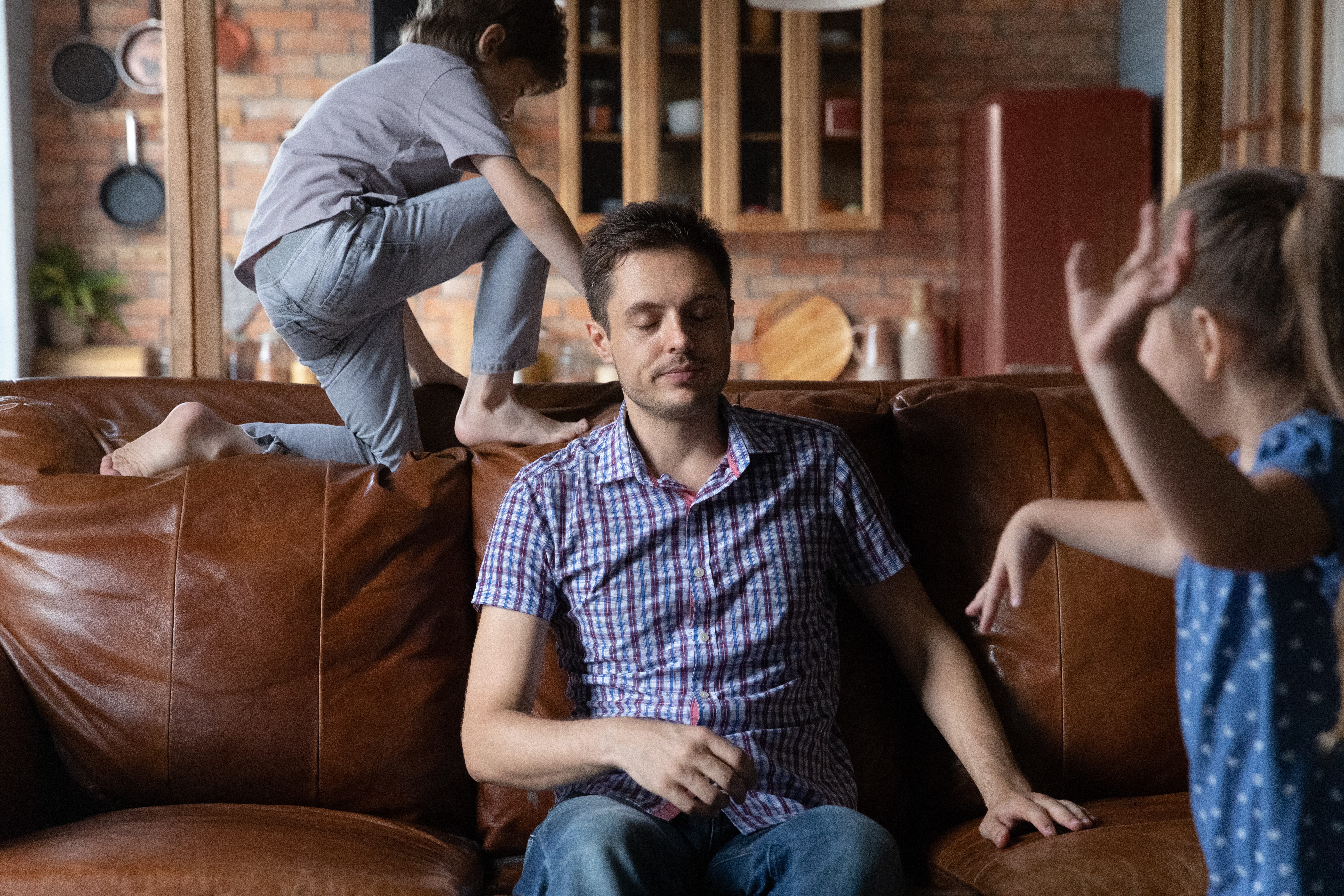 A father feeling exhausted due to his kids making noise in the room | Source: Shutterstock