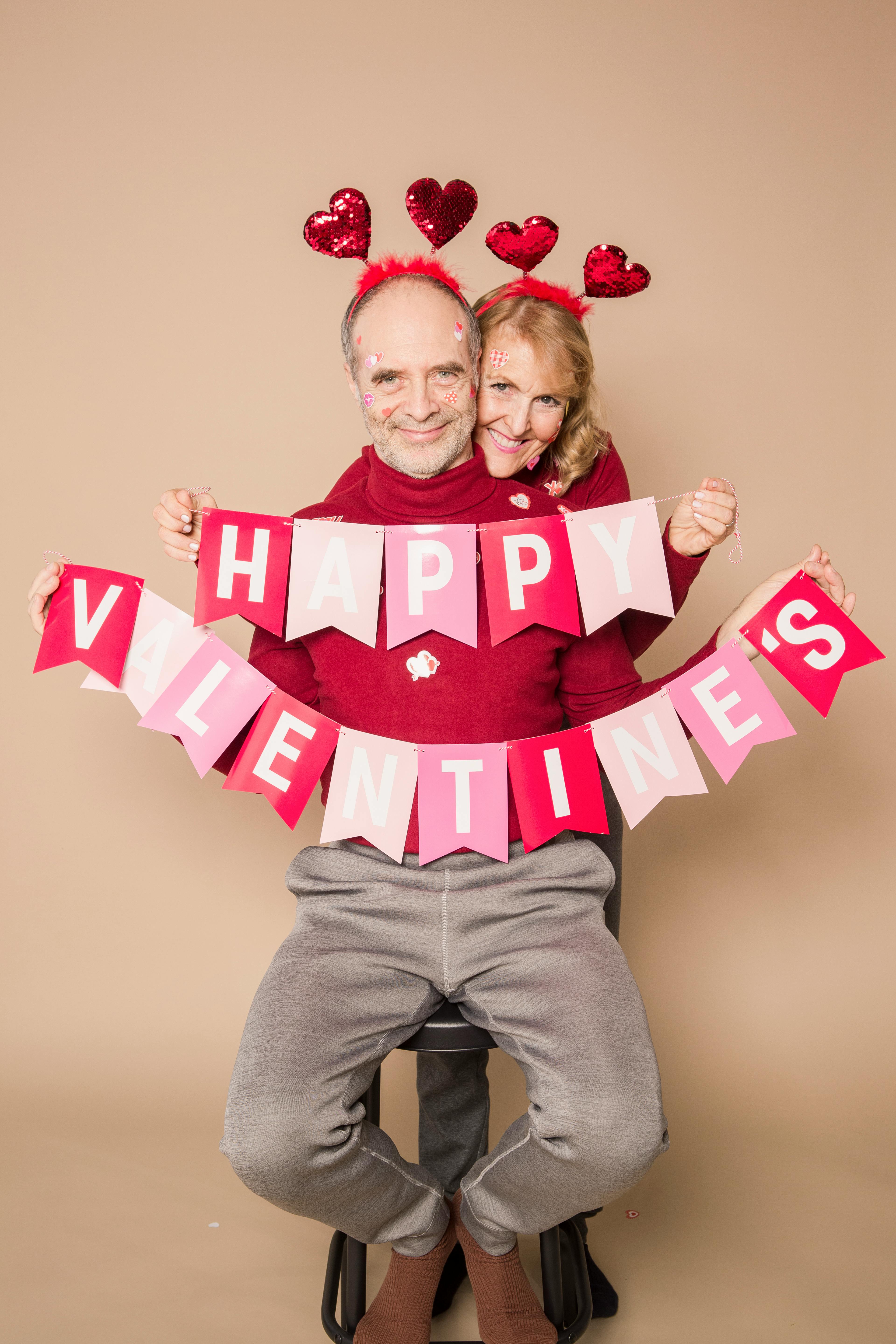 A couple in matching outfits holding a hanging decoration that says 