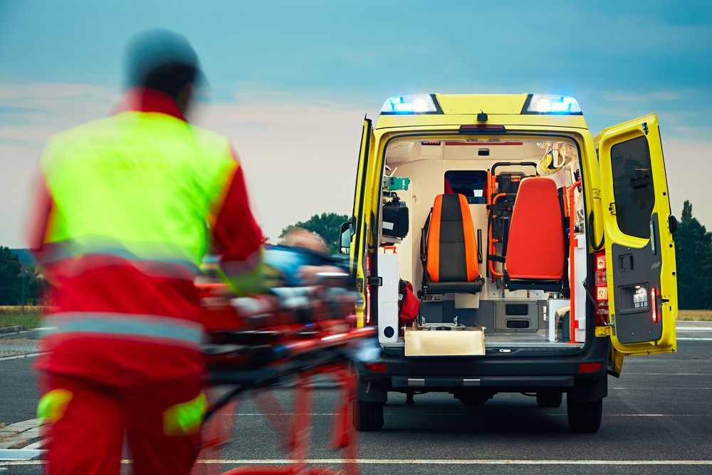 Paramedic pulling a stretcher with a patient to the ambulance. | Source: Shutterstock