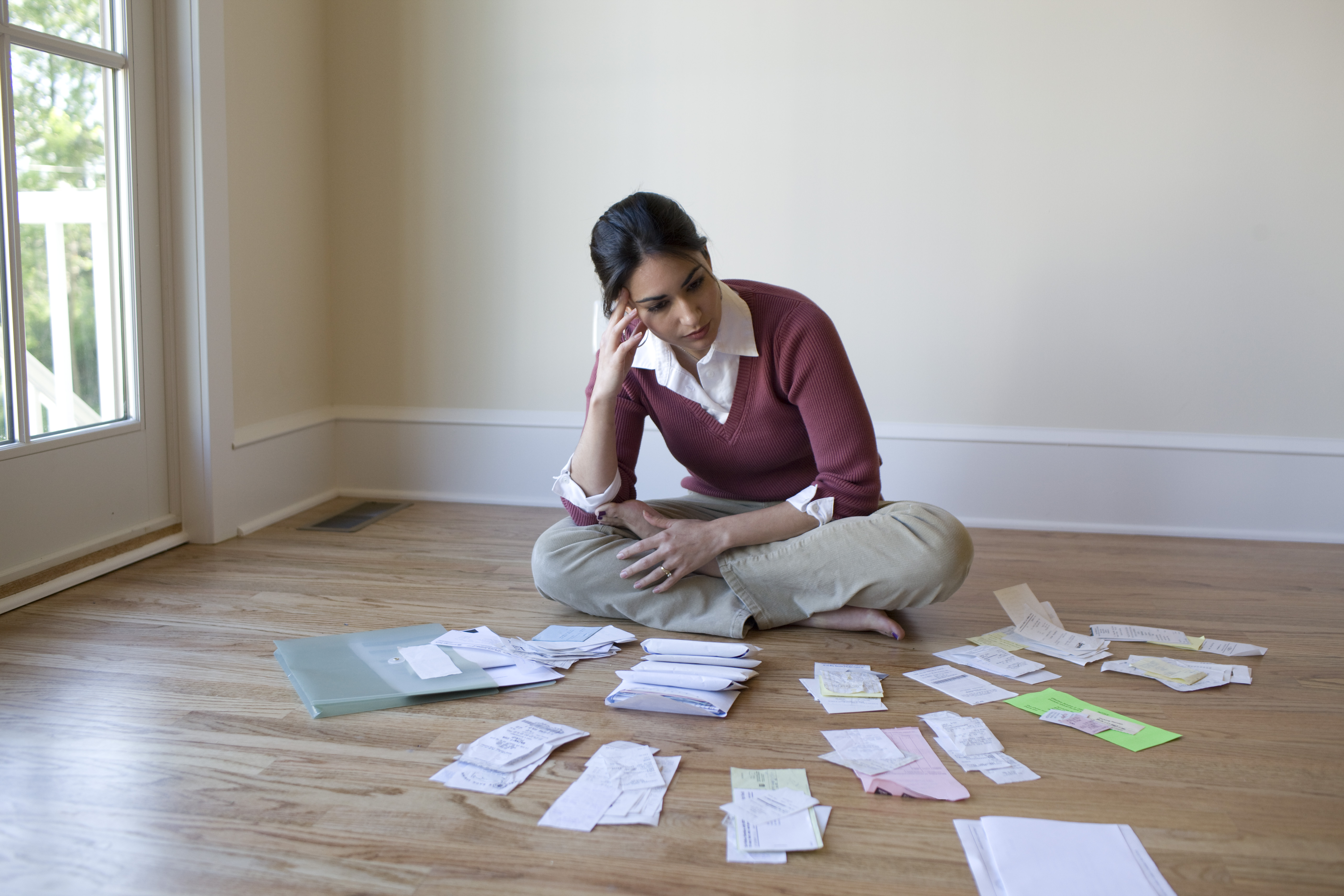 Woman looking at bills and receipts on floor | Source: Getty Images