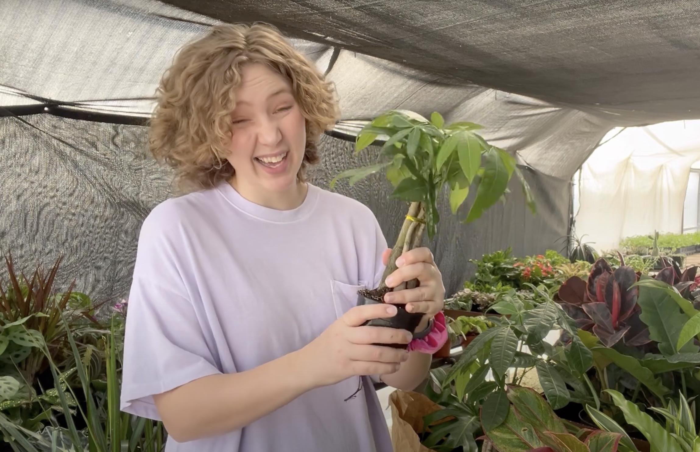 A woman holding a smaller money tree | Source: YouTube/Renata's Garden