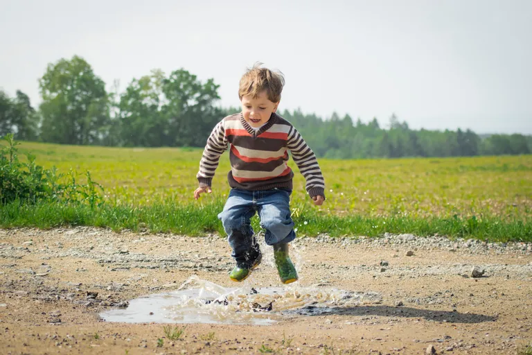 A little boy jumping on a puddle while playing outdoors | Photo: Pexels