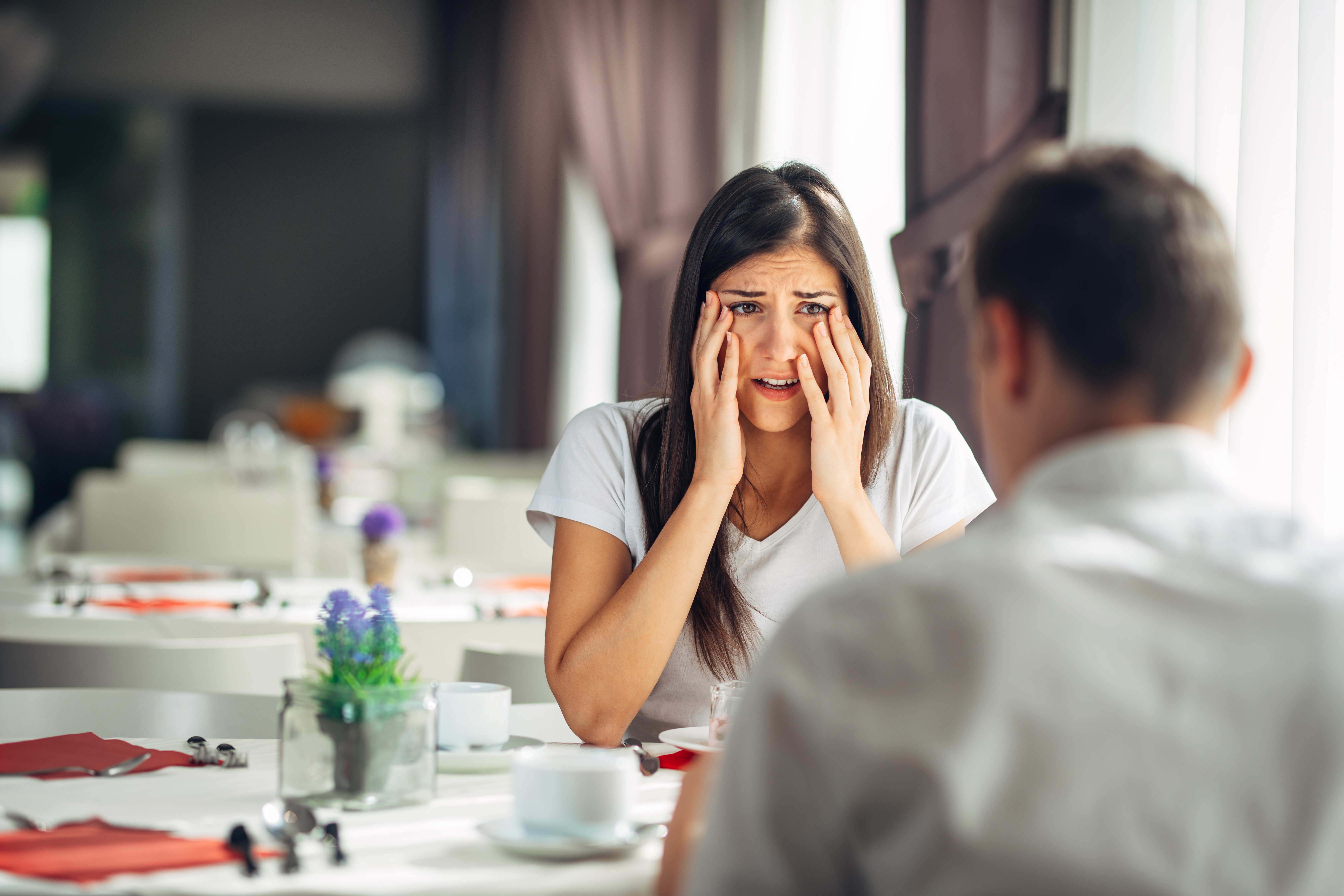 Woman looking surprised while dining with a man | Shutterstock