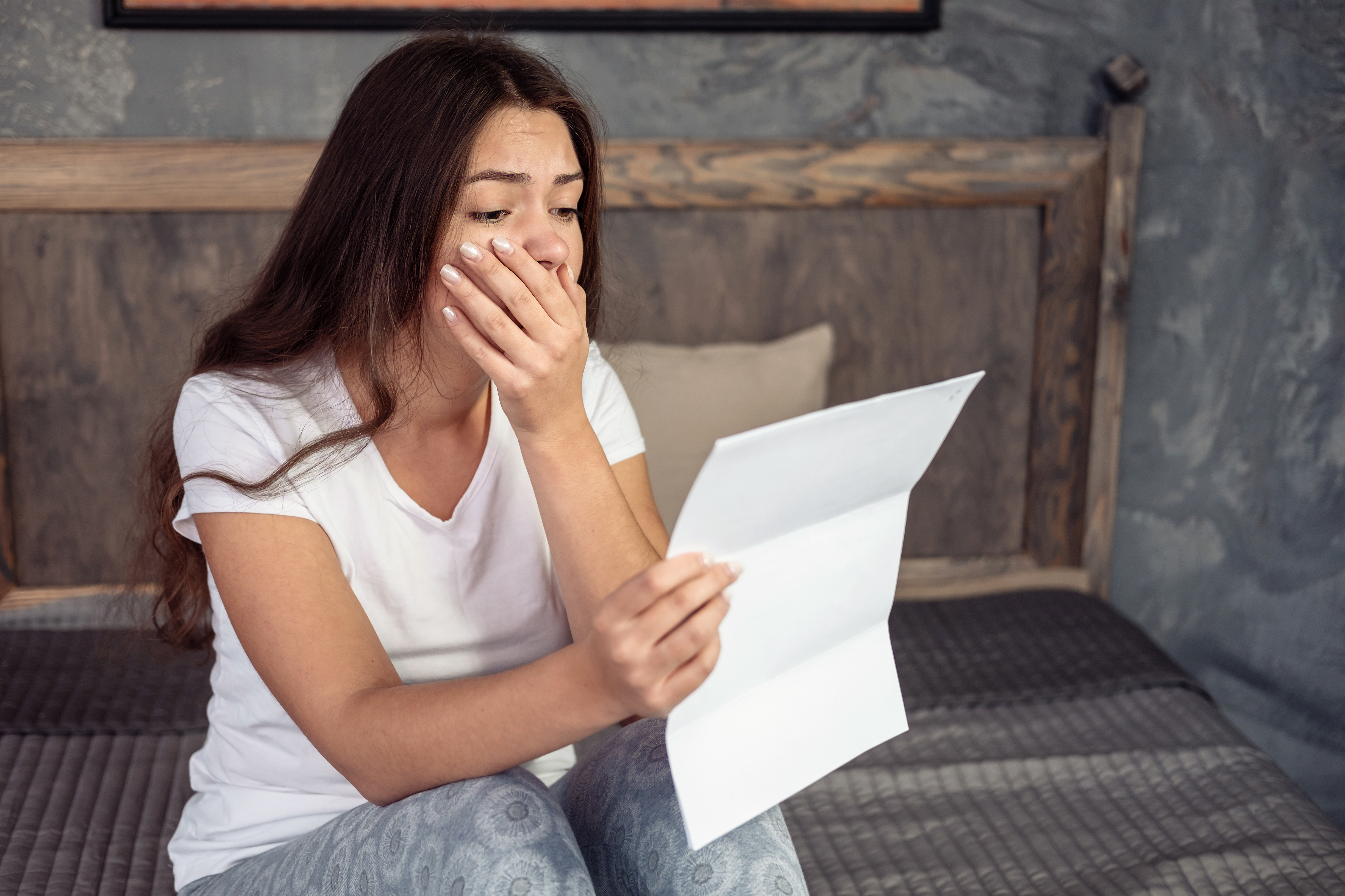 A shocked young woman reading a letter | Source: Shutterstock