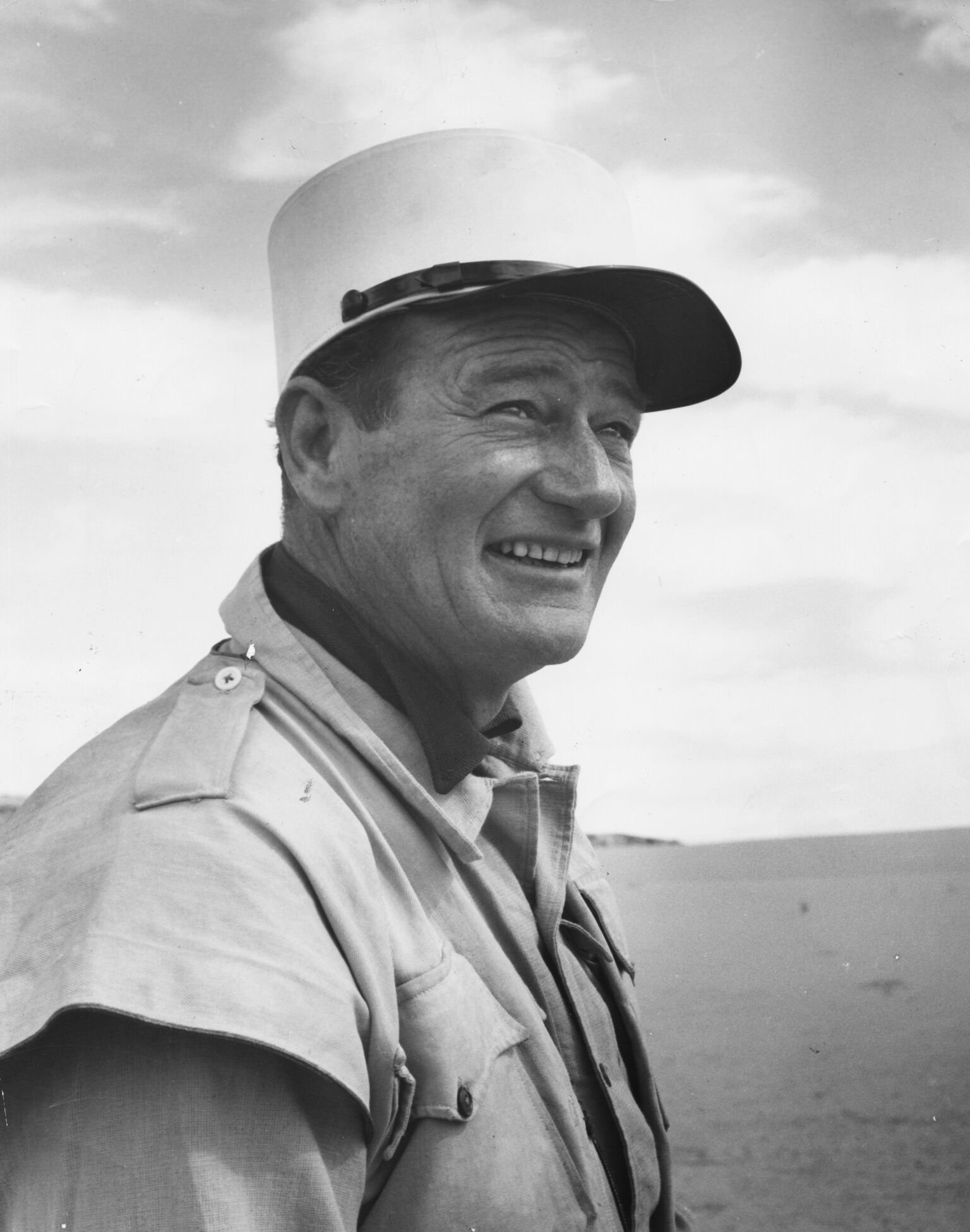 John Wayne in costume, standing in a desert landscape filming the movie "Legend of the Lost" | Getty Images