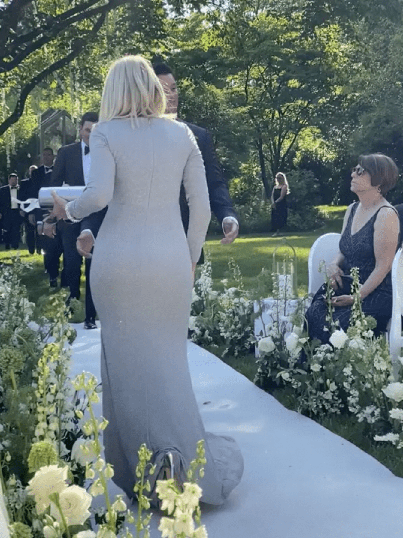 Eine Frau in einem cremefarbenen Kleid geht den Gang entlang, während der Bräutigam an ihr vorbeigeht. | Quelle: reddit.com/r/weddingshaming