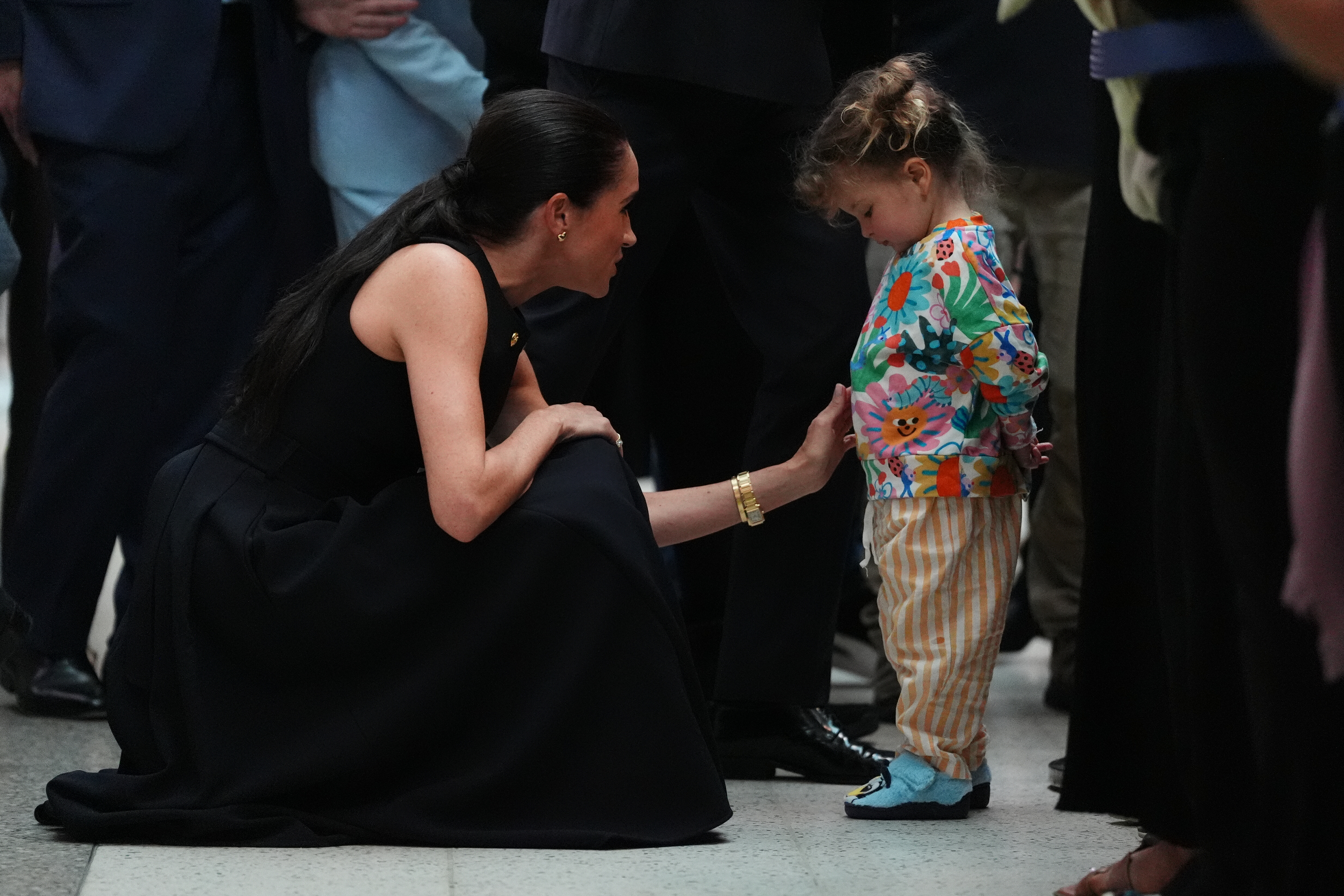 The Duchess of Sussex knelt down to speak with a young child, creating a tender moment during the couple's visit to the Royal Children's Hospital on 14 April 2026. | Source: Getty Images