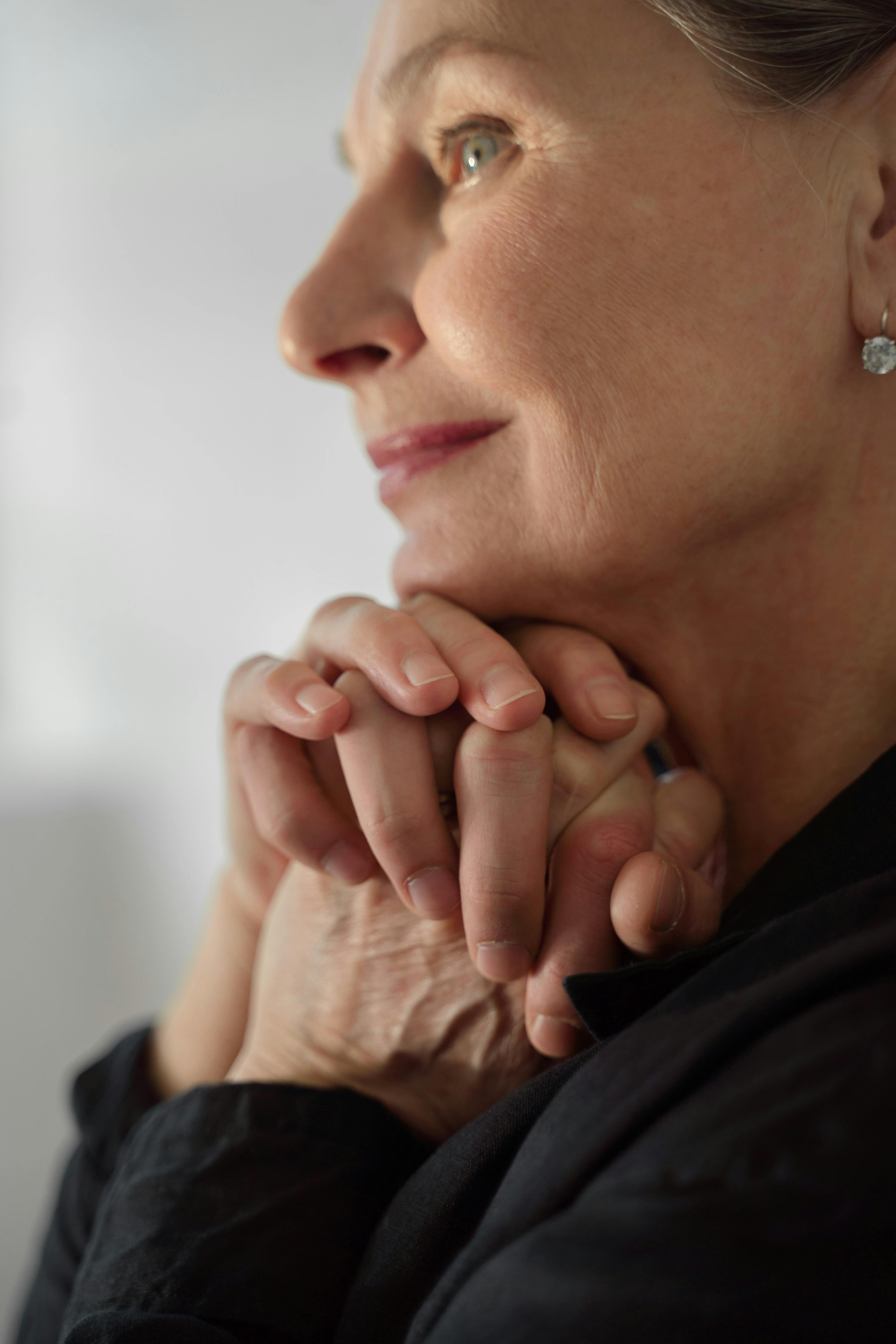 A side-view of an emotional woman clutching her hands together | Source: Pexels