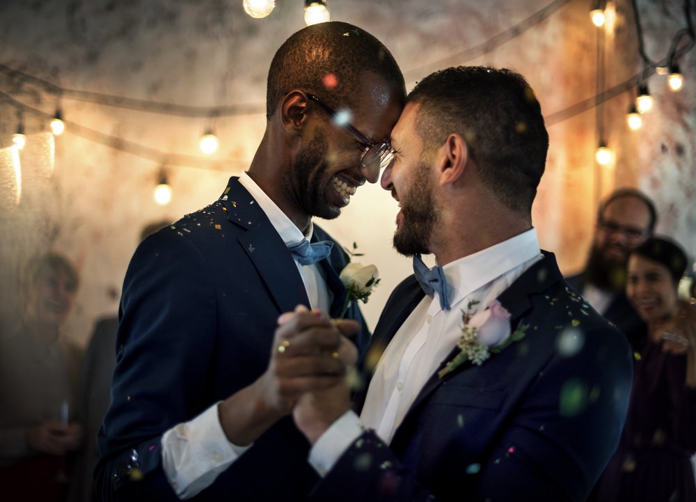 Pareja homosexual luciendo trajes formales mientras baila. | Foto: Shutterstock