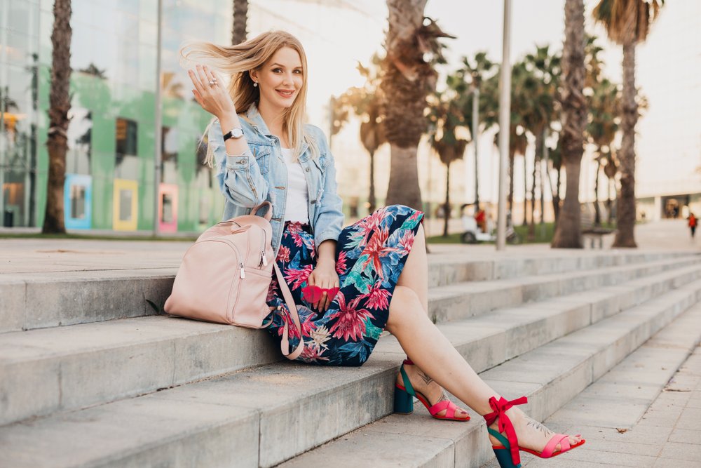 Mujer sentada en unas escaleras usando una falda floreada a la altura de las rodillas. | Foto: Shutterstock Mujer sentada en unas escaleras usando una falda floreada a la altura de las rodillas. | Foto: Shutterstock