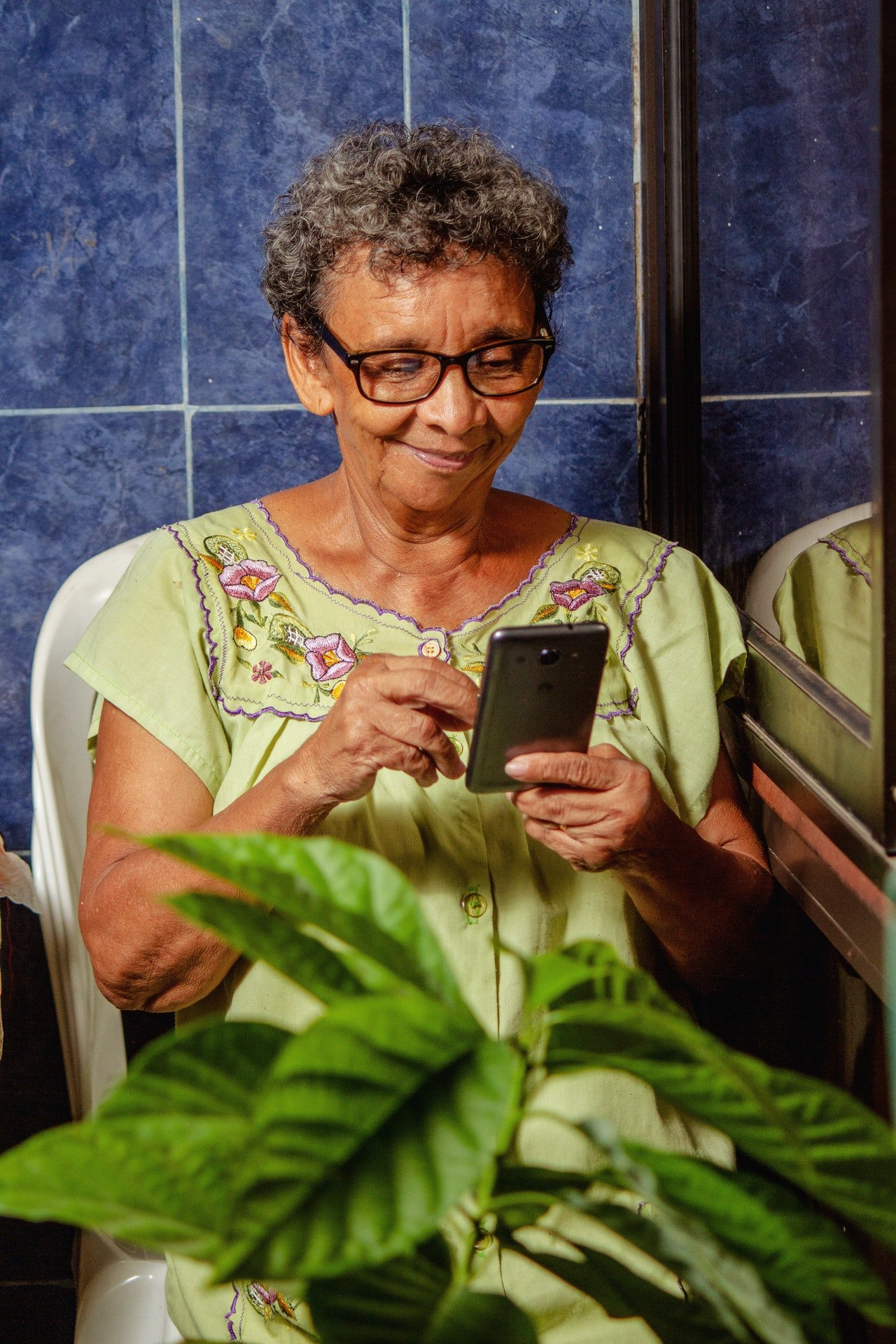 Una mujer mayor sonrie mientras revisa su teléfono. | Foto: Pexels