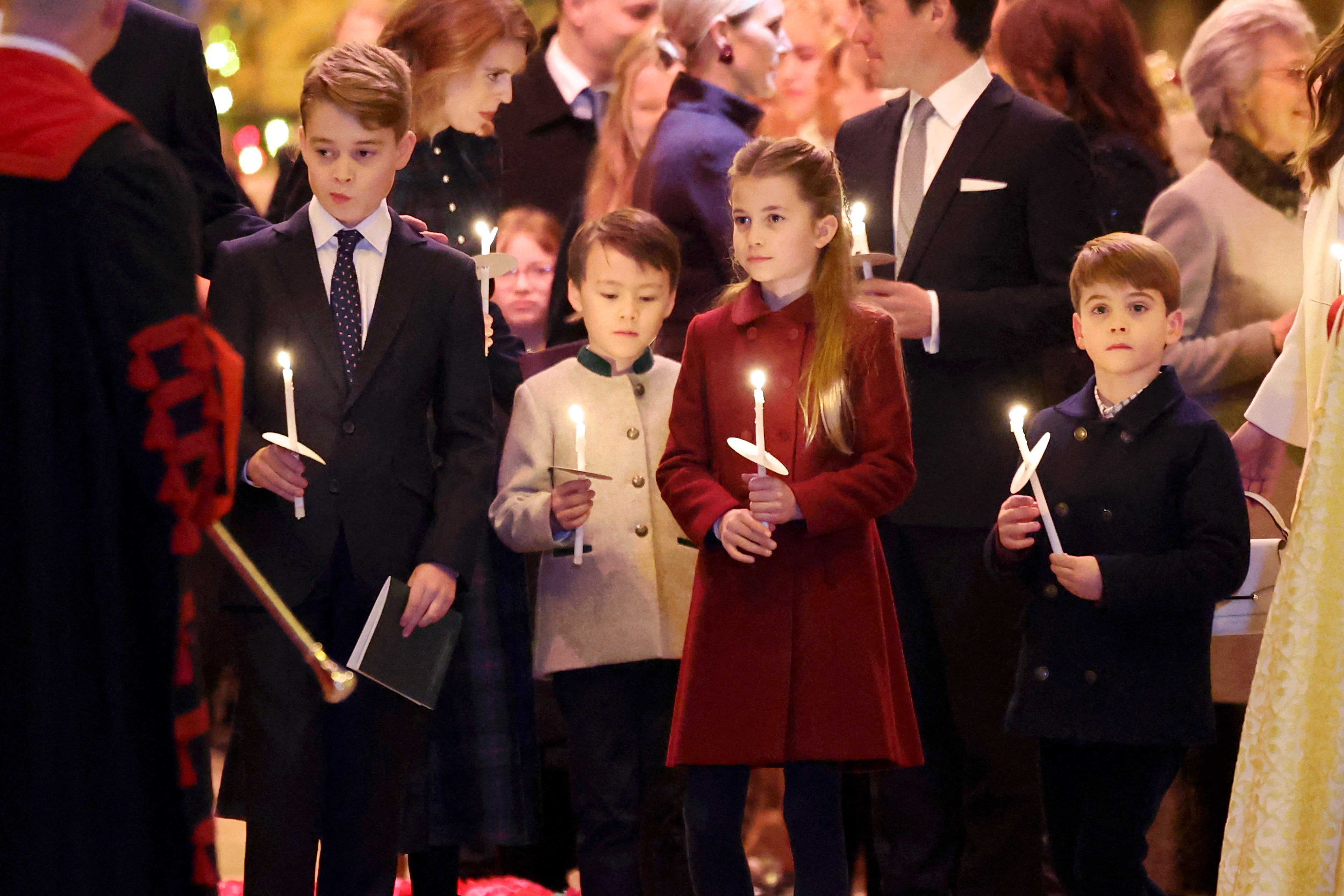 Prince George, Christopher Woolf Mapelli Mozzi, Princess Charlotte, and Prince Louis held lighted candles during the "Together At Christmas" Carol Service at Westminster Abbey on December 8, 2023, in London. | Source: Getty Images