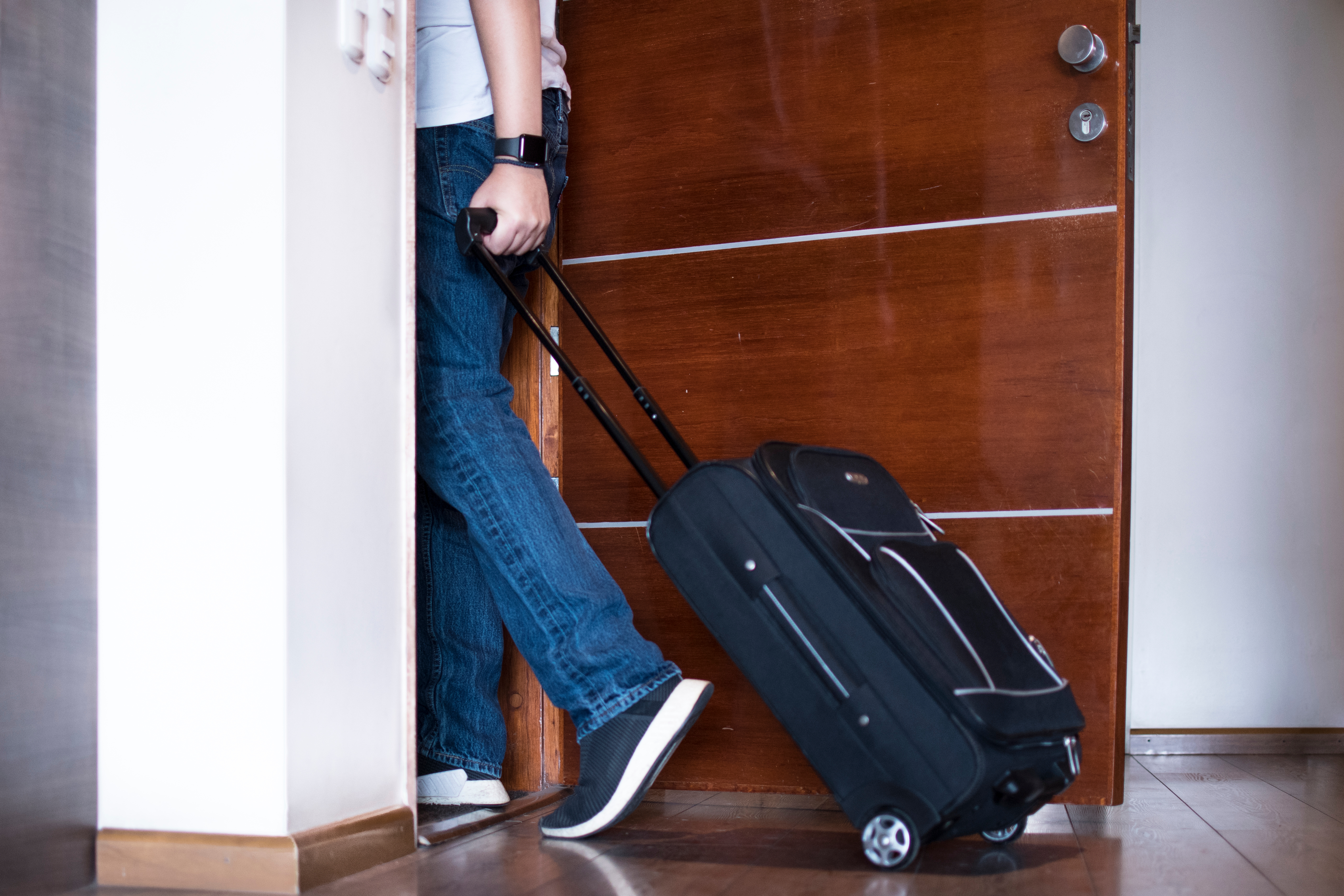 Man leaves house with his trolley luggage | Source: Shutterstock.com