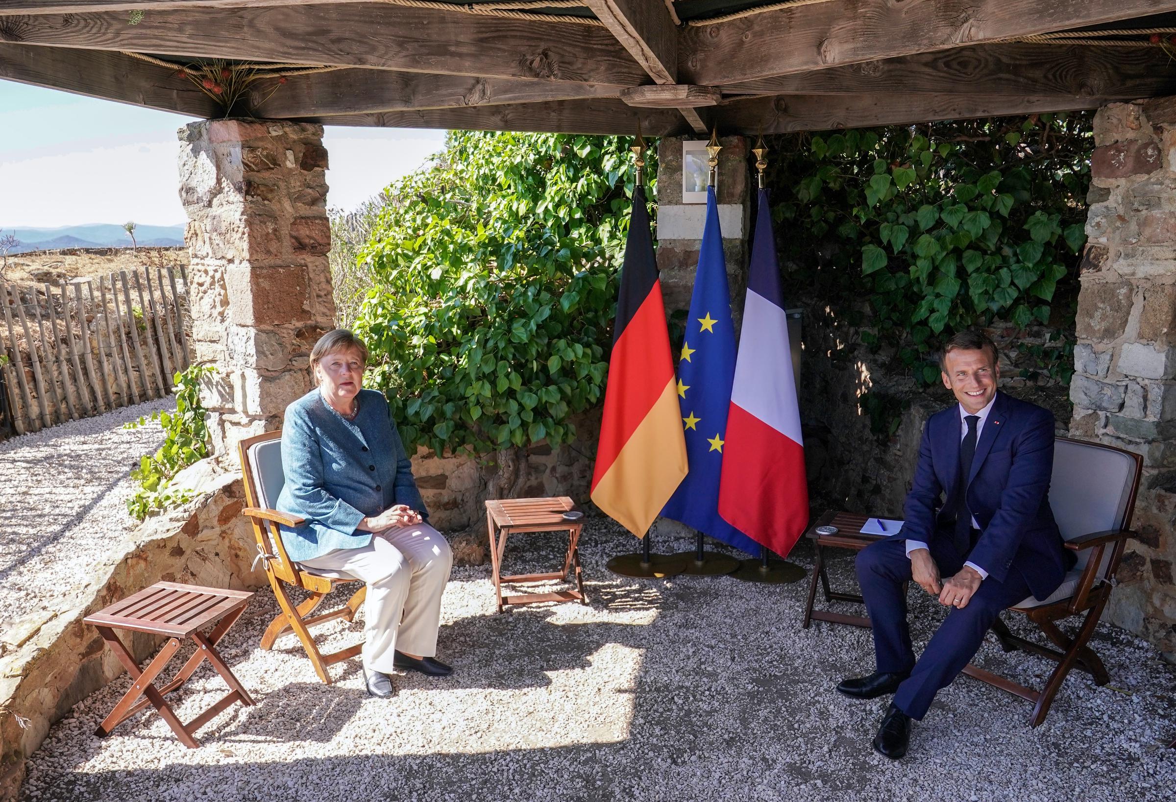 Emmanuel Macron sits next to German Chancellor Angela Merkel (CDU), at the start of the talks in the garden at the summer residence of the Head of State in Fort de Bregancon on August 20, 2020 | Source: Getty images