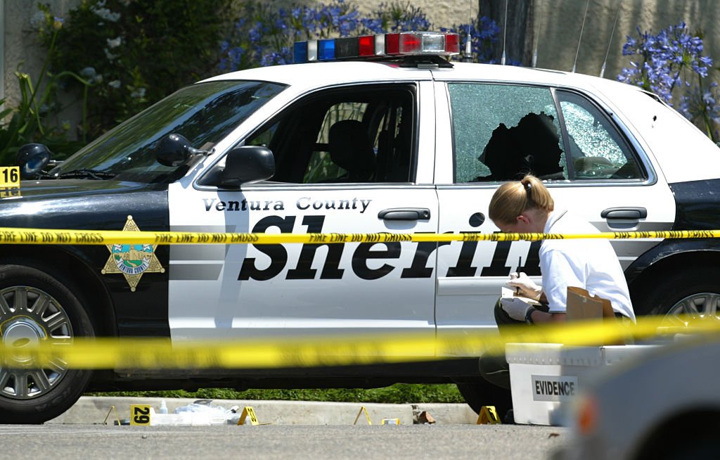 A Crime scene investigator examines a bullet hole in the side of a patrol car that in which a deputy was shot on May 31, 2005 | Photo: Getty Images