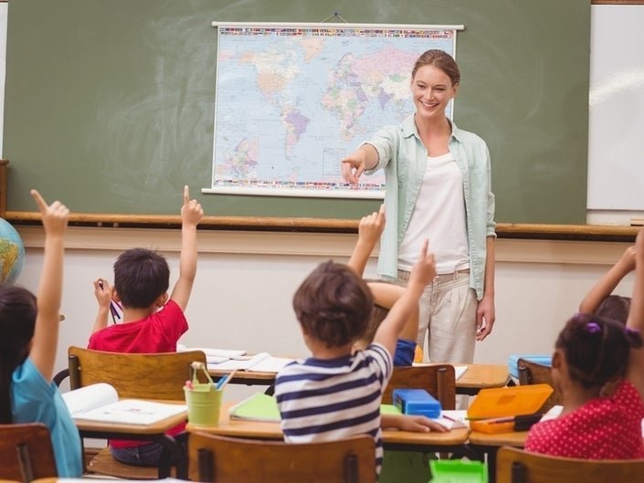 Happy elementary teacher aiming at school kids to answer her question | Photo: Shutterstock