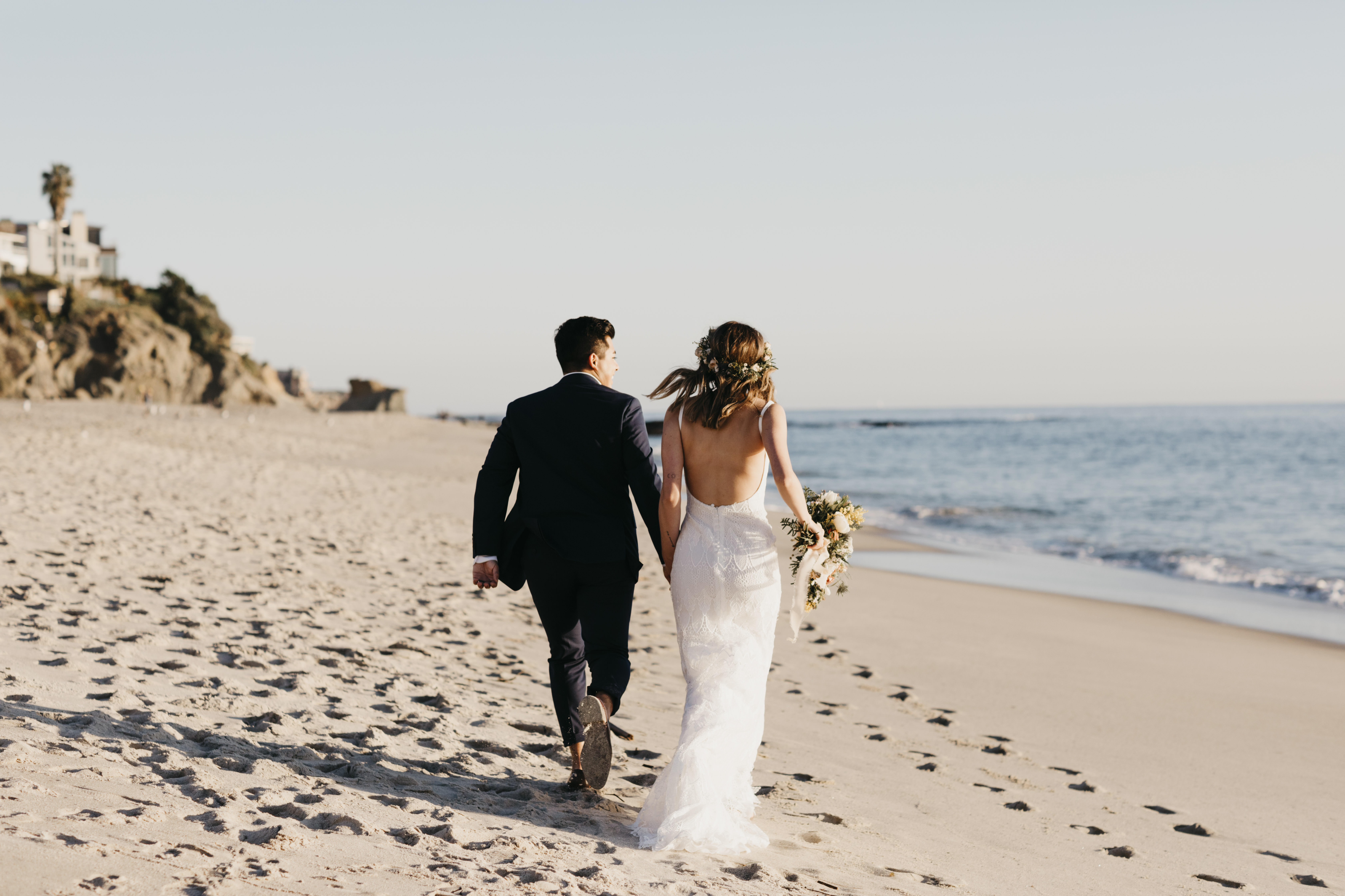 Rear view of happy bridal couple running at the beach | Source: Getty Images