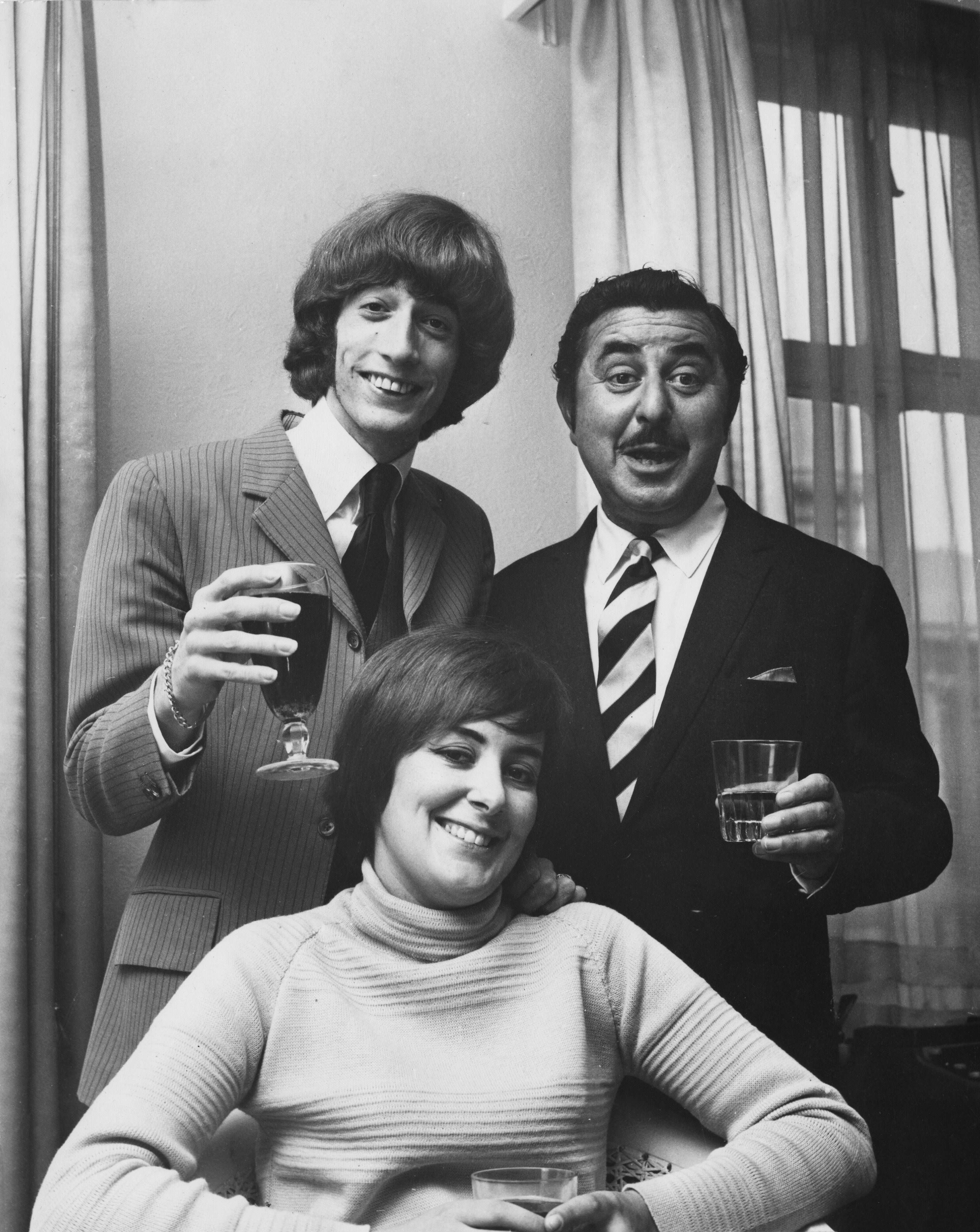 Robin Gibb with his first wife, Molly, and managing director of NEMS Enterprises, Vic Lewis, celebrating Gibb's signing of a contract with NEMS, 5th September 1969. | Source: Getty Images