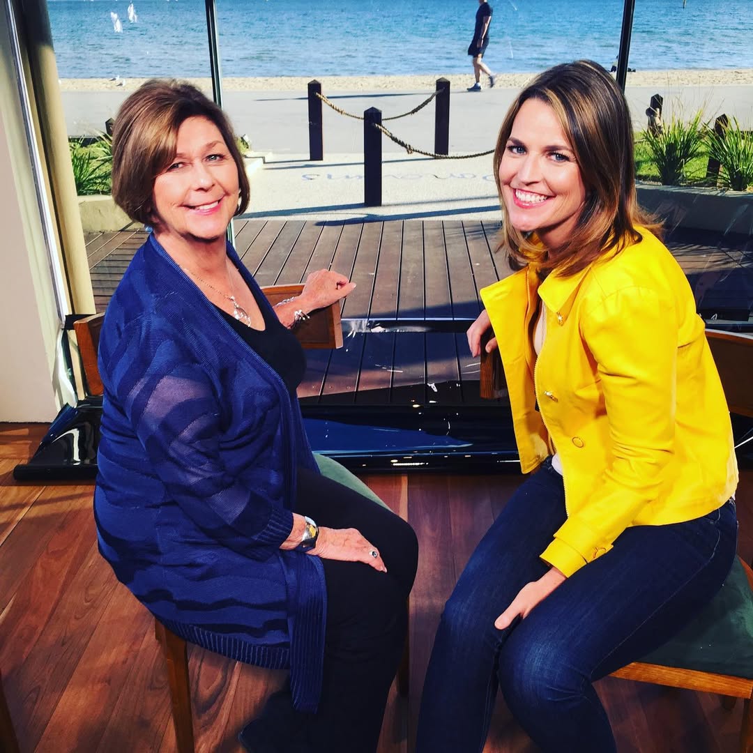 Nancy Guthrie and her daughter Savannah sit facing each other on stools indoors, smiling toward the camera, with a beach and water visible through large windows behind them, from a post dated January 27, 2021. | Source: Instagram/savannahguthrie
