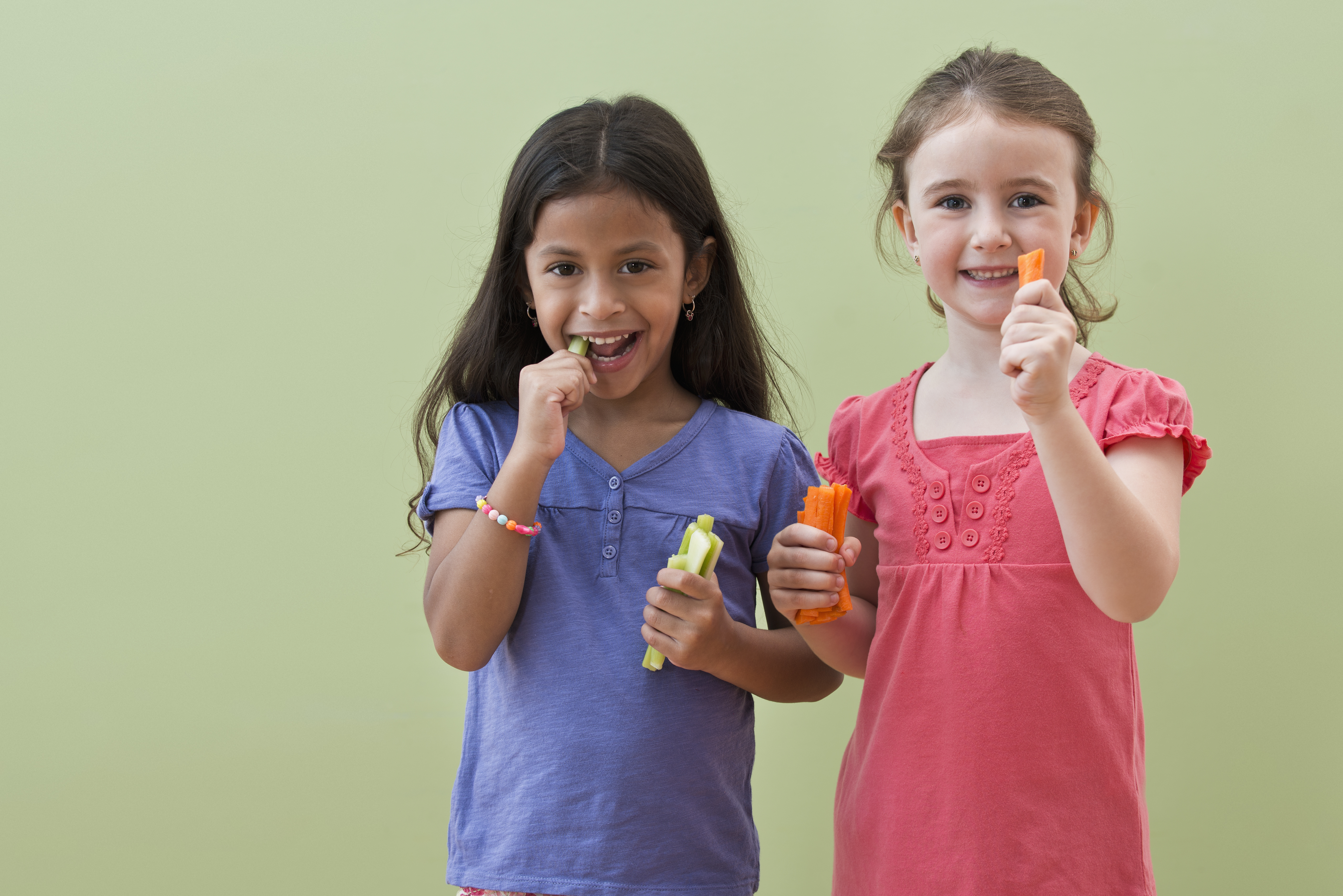 Girls eating vegetable sticks together | Source: Getty Images