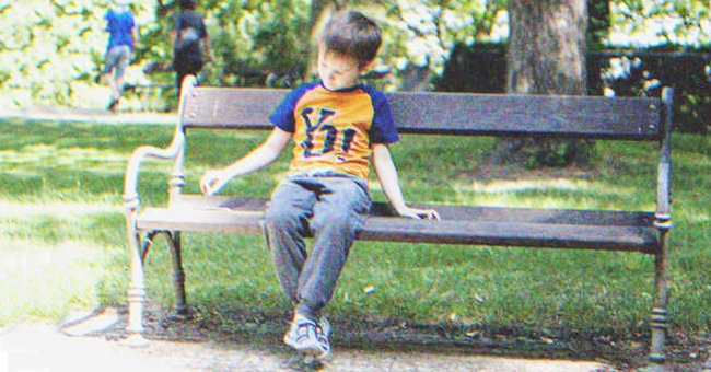 Niño sentado solo en el banco de un parque público. | Foto: Shutterstock