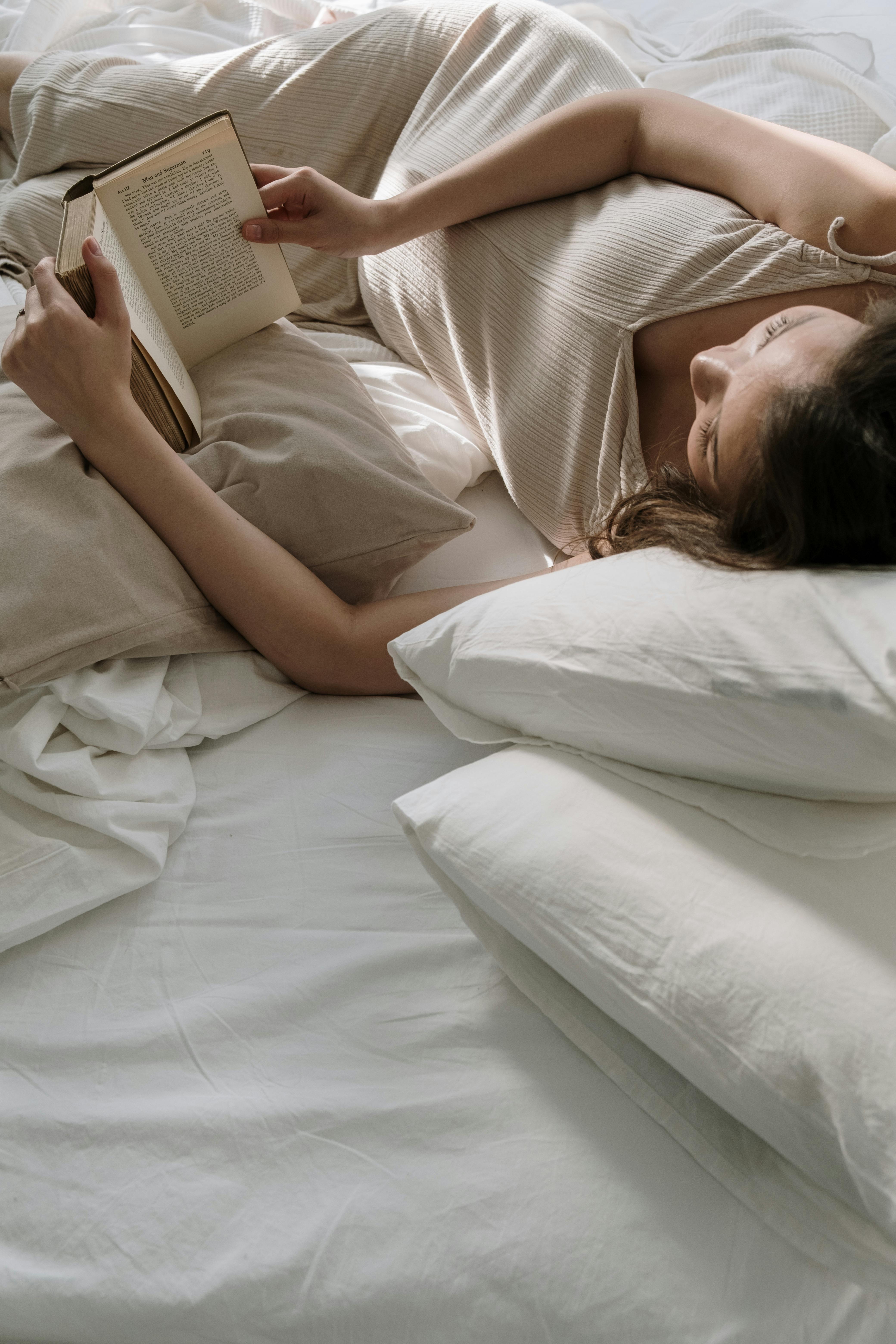 A woman lying in bed reading a book | Source: Pexels