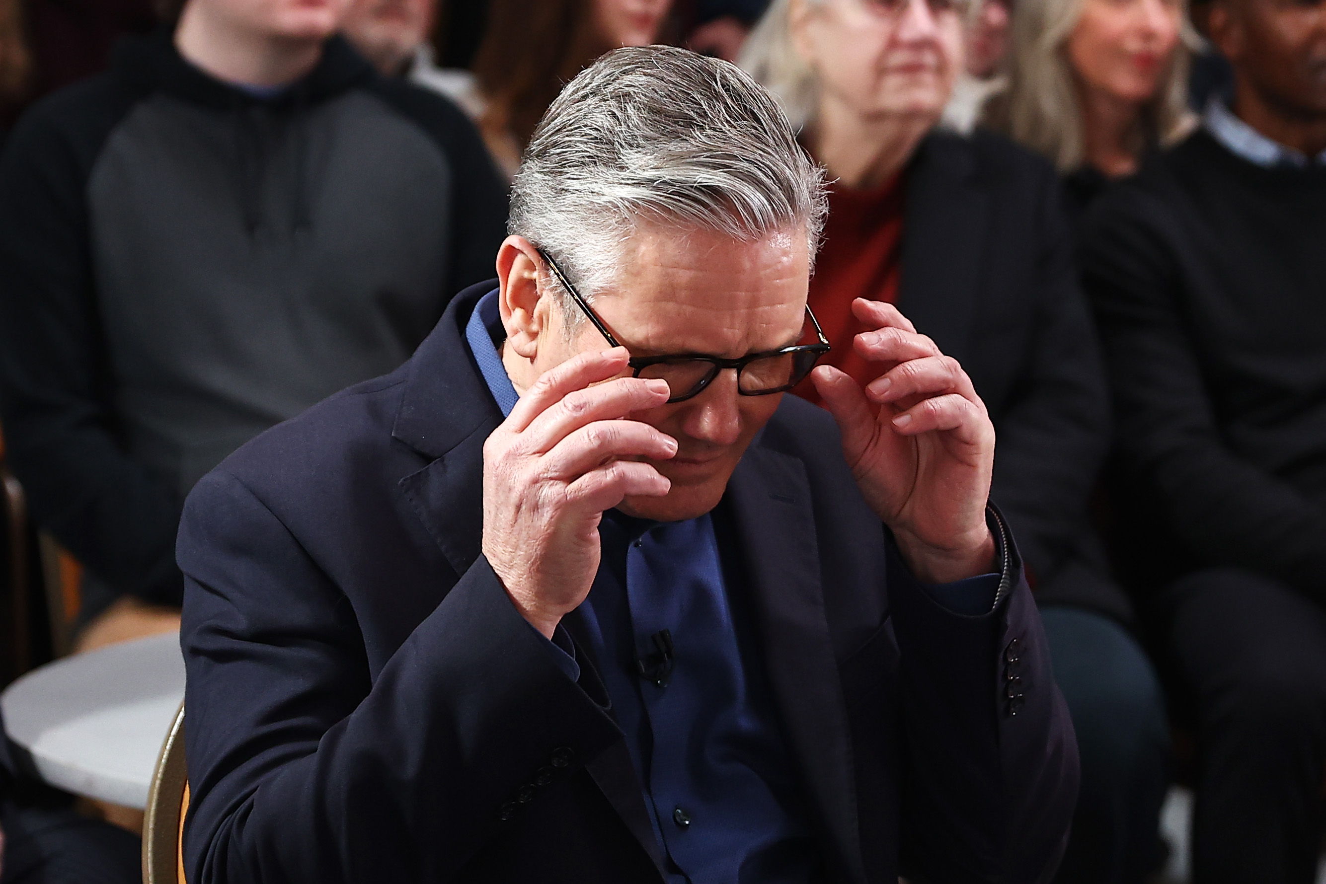 Sir Keir Starmer adjusts his glasses as he waits to deliver his speech at Horntye Park Sports Complex on February 5, 2026, in England. | Source: Getty Images