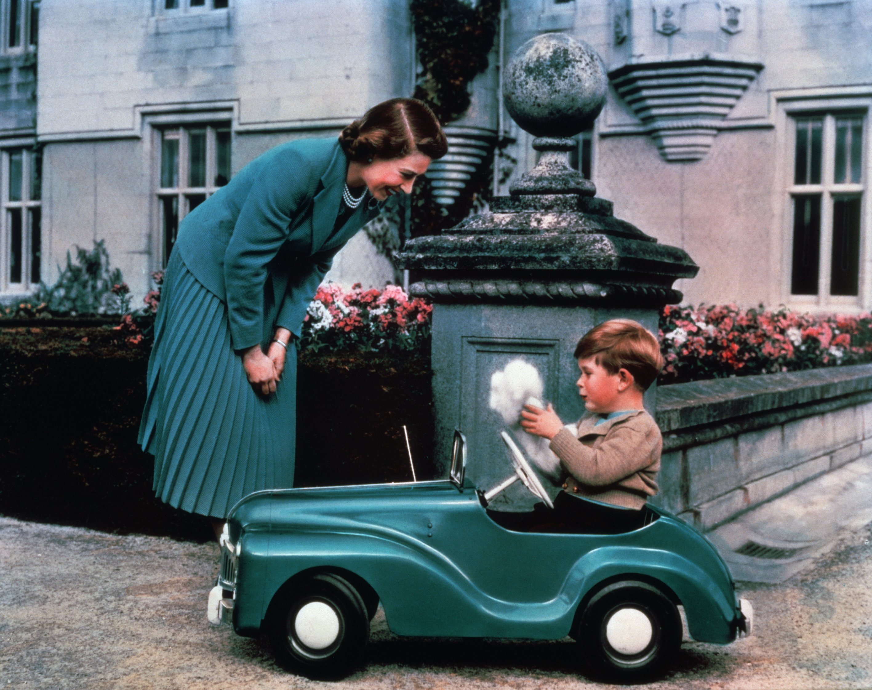 Queen Elizabeth watches her son Prince Charles driving in a toy car on the grounds of Balmoral Castle, circa 1952 | Source: Getty Images