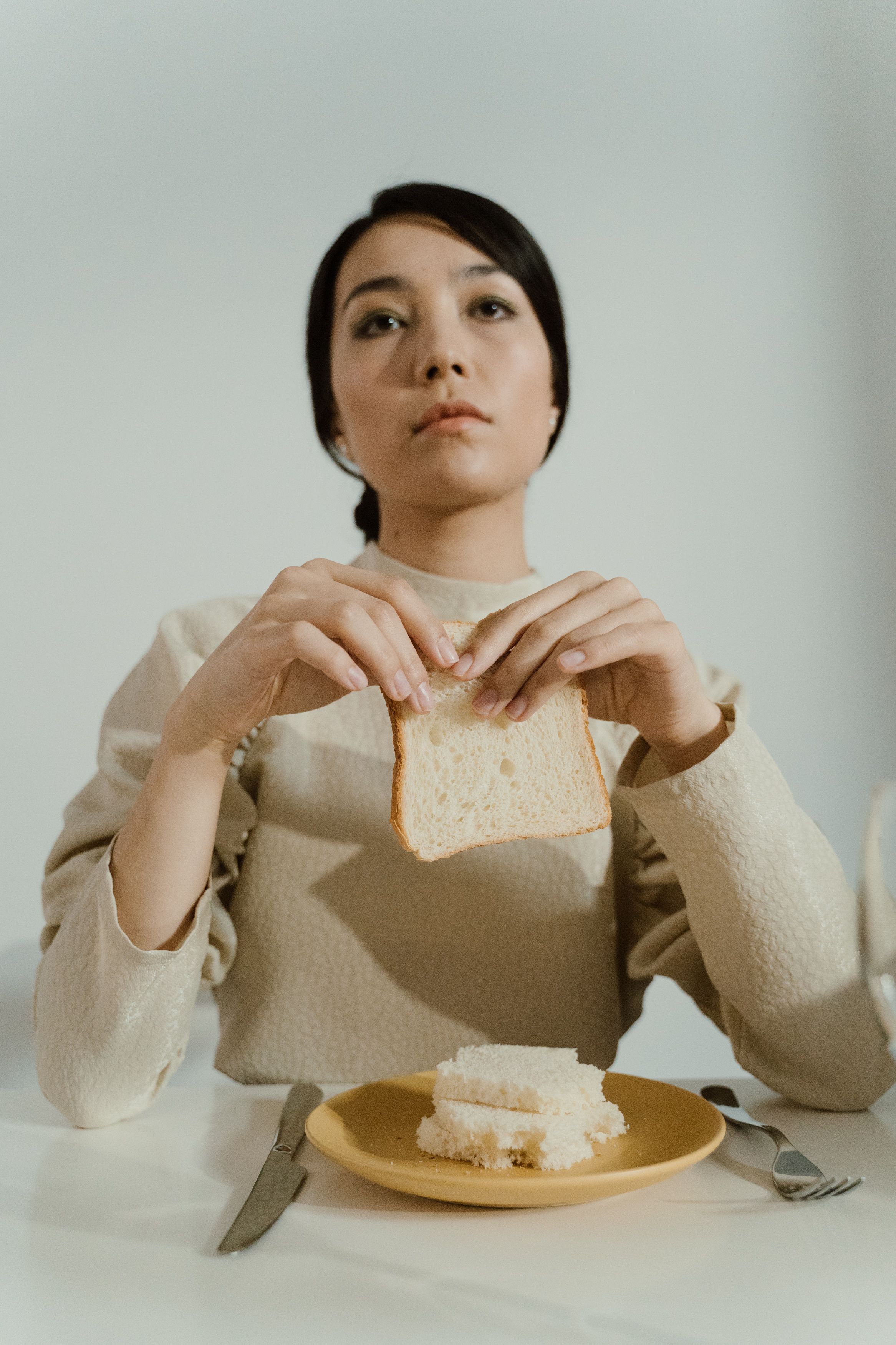 Woman contemplating as she holds a piece of bread | Source: Pexels