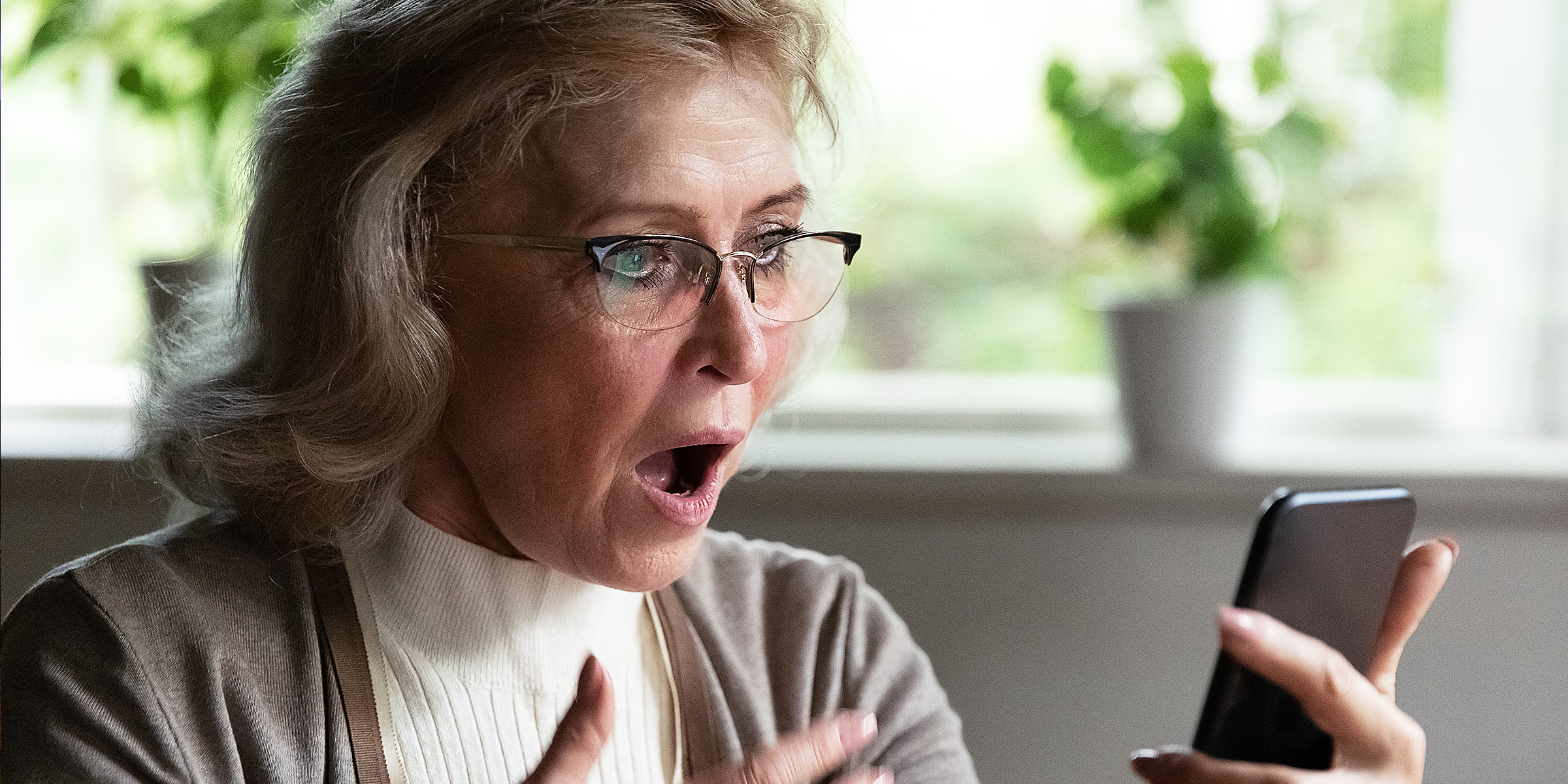 A woman staring at her phone in shock | Source: Shutterstock