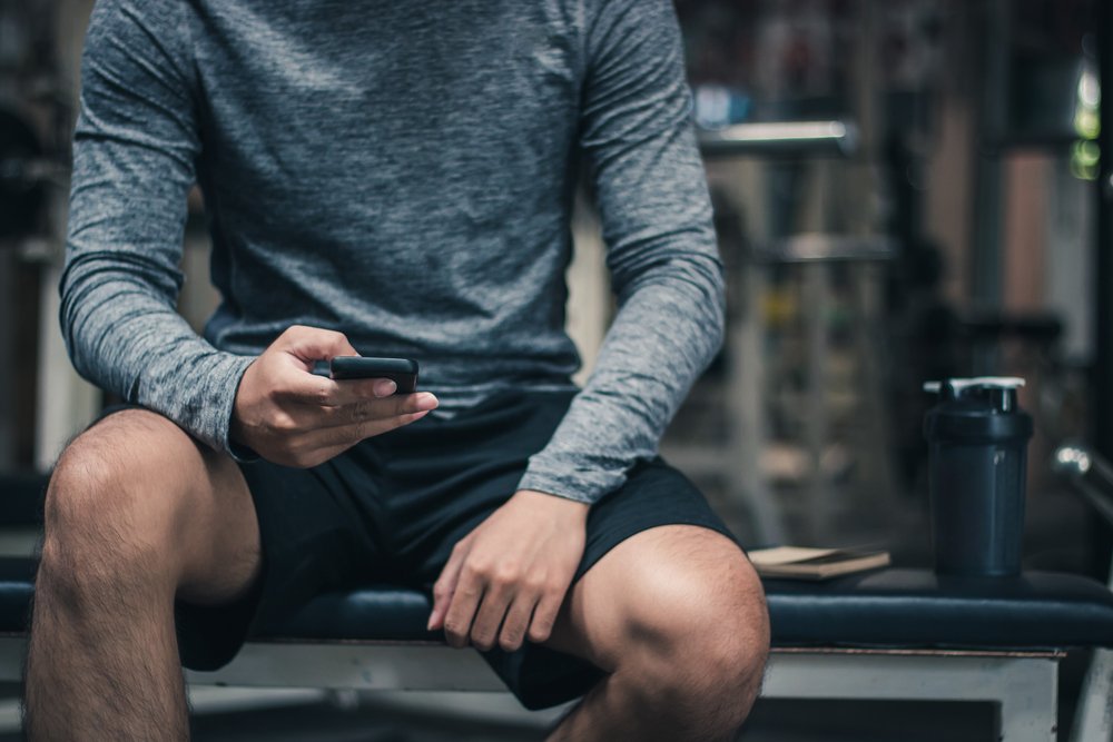Man answering mobile phone in gym locker. | Image: Shutterstock