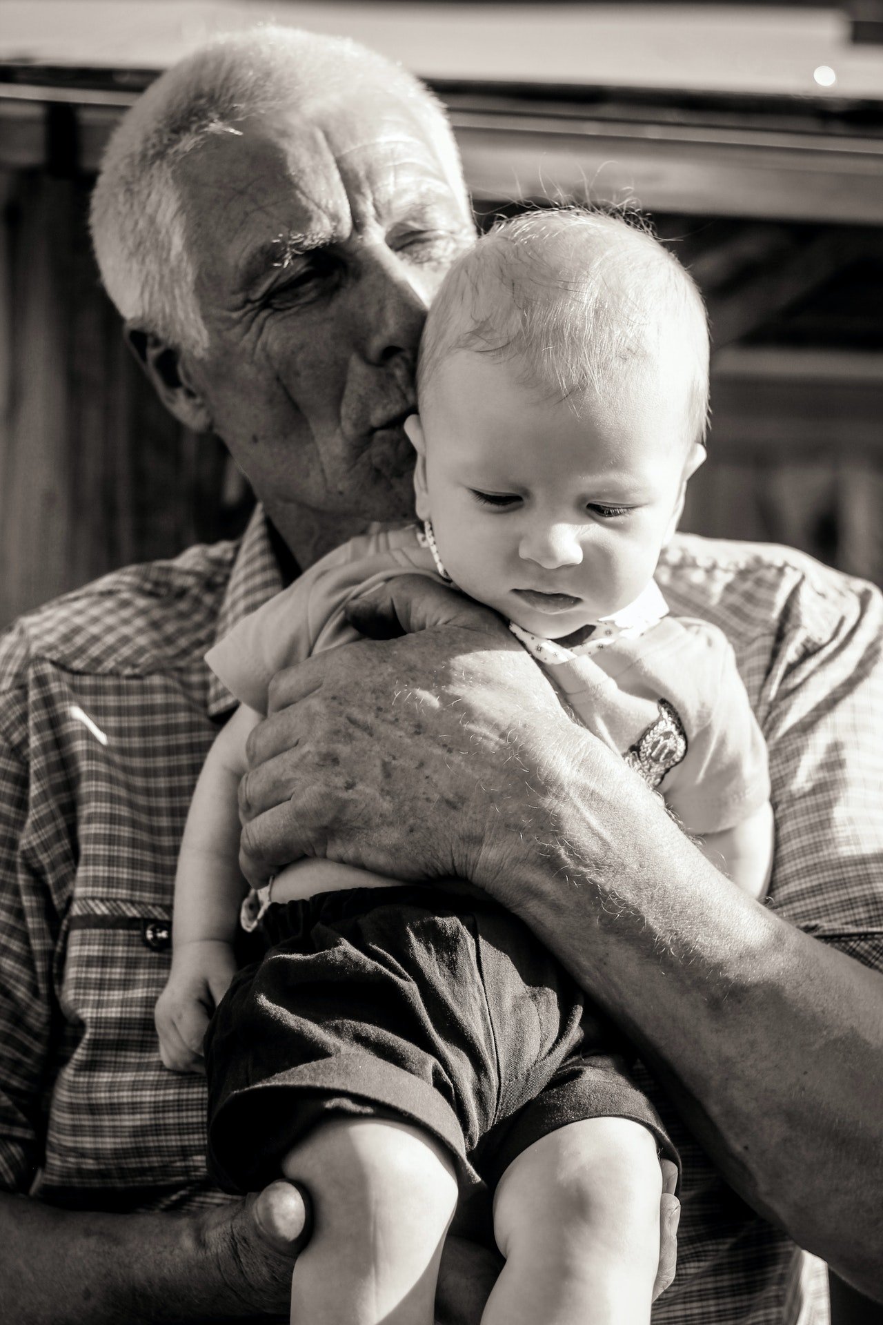 Un anciano con un bebé en sus brazos. | Foto: Pexels