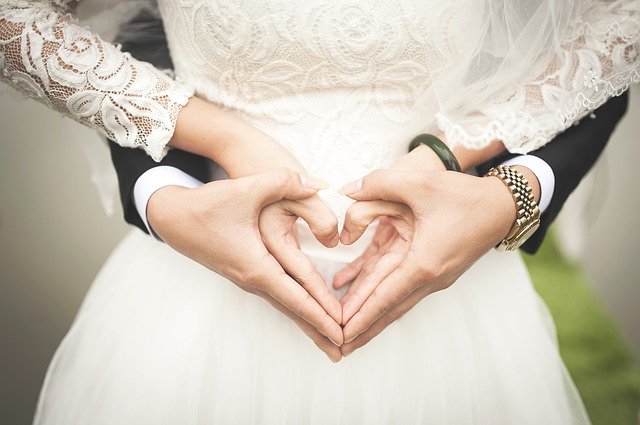 A bride and groom create a heart with their hands | Photo: Pixabay