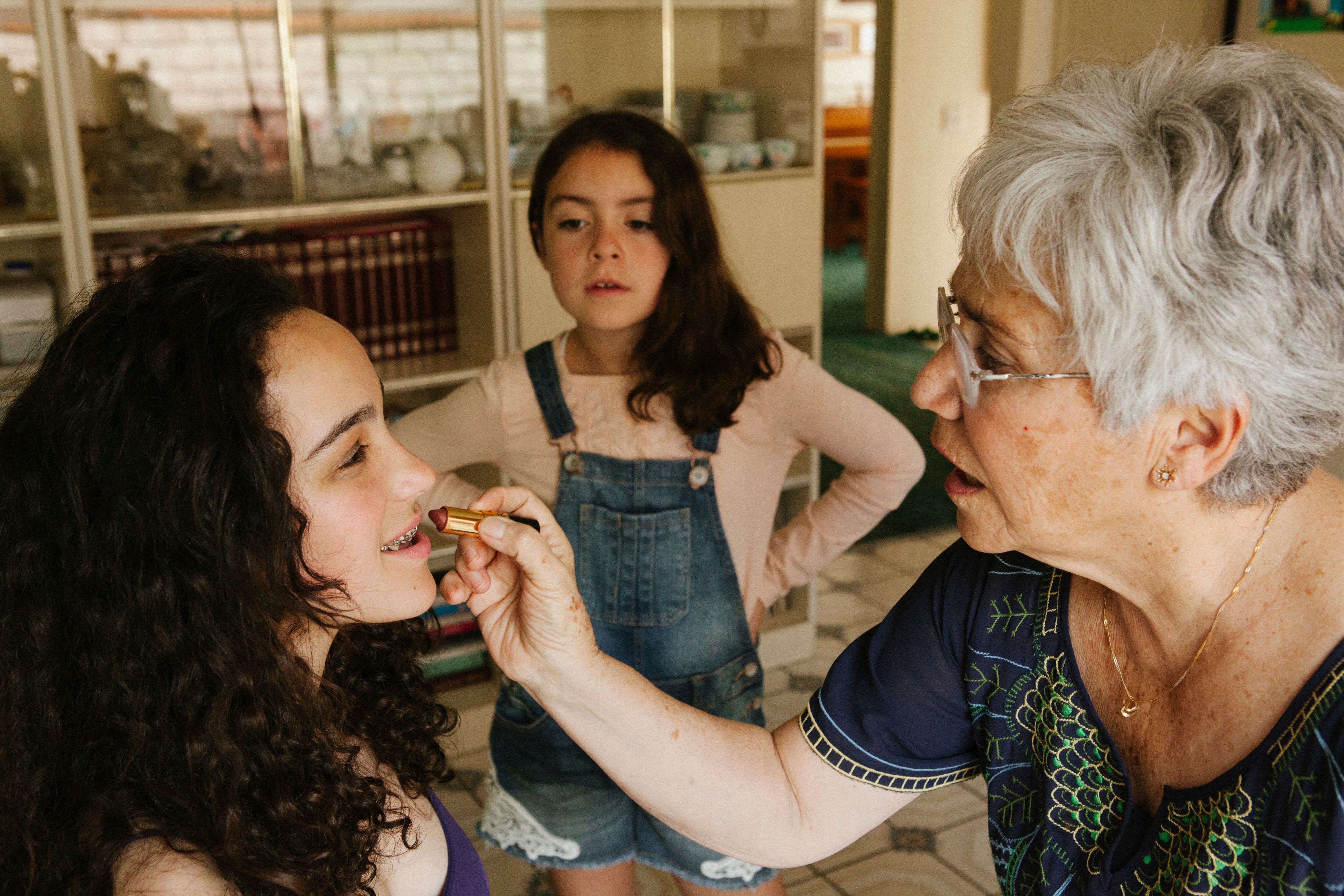 A grandmother putting lipstick on her granddaughter | Source: Getty Images