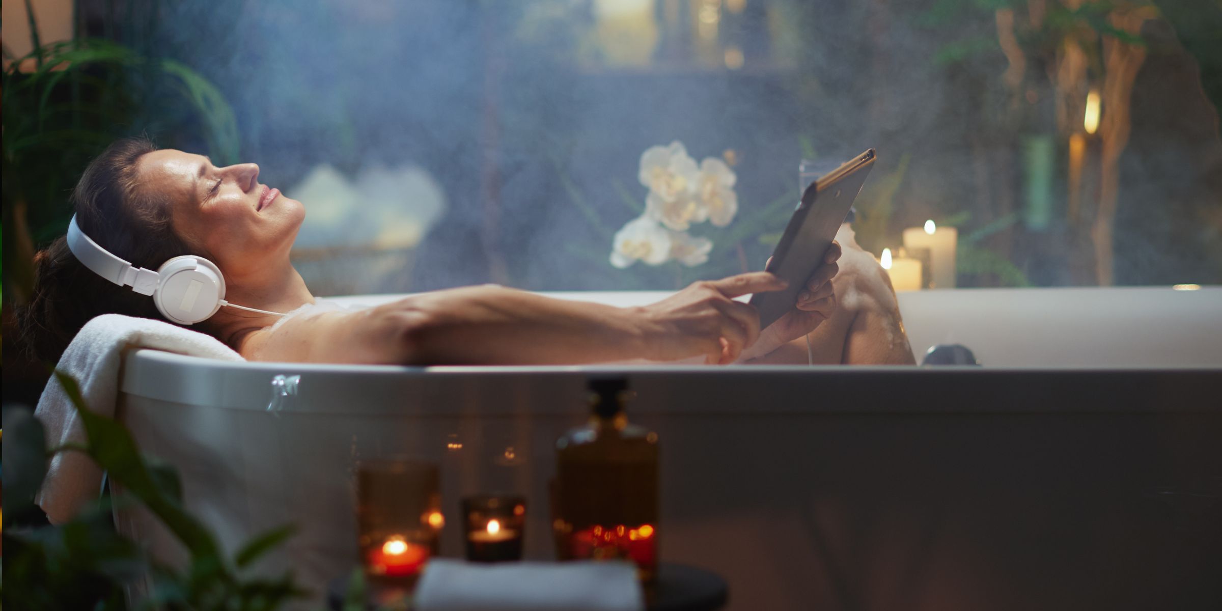 Woman relaxing in a bathtub with headphones on | Source: Shutterstock